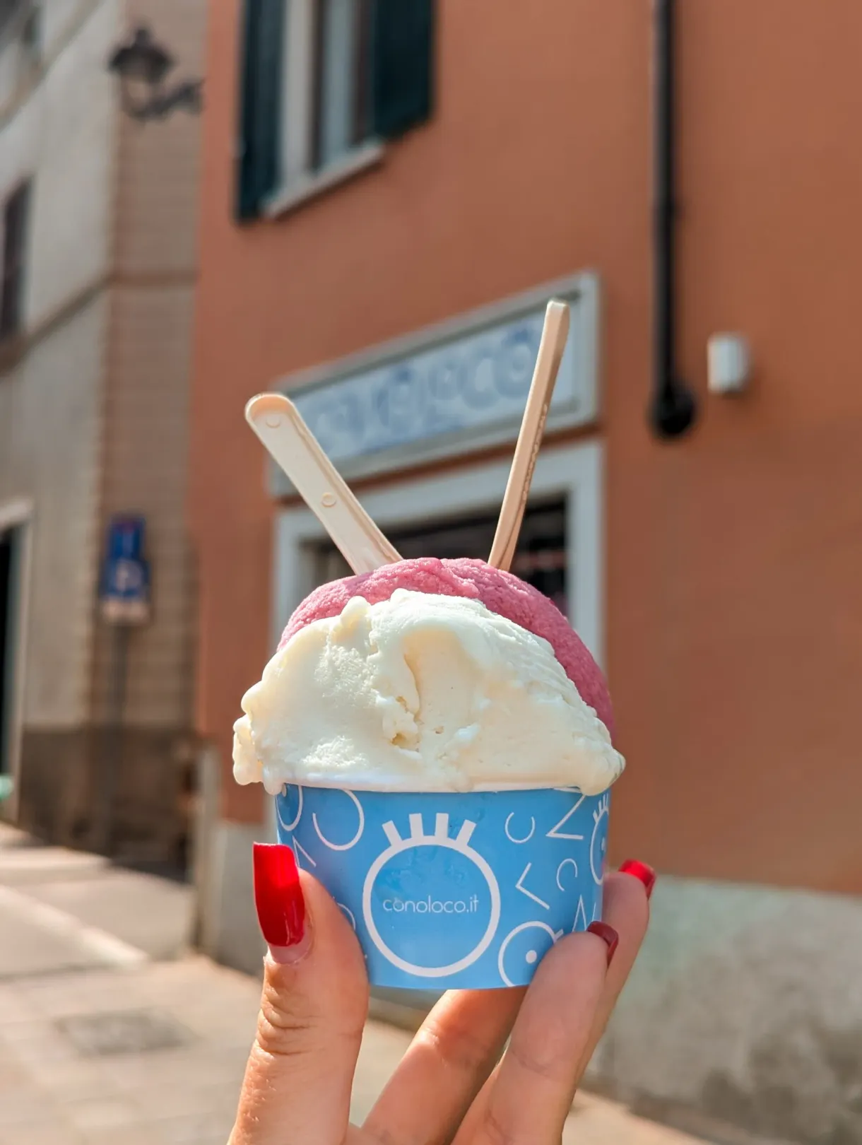Glace rose et blanche tenue devant une façade colorée