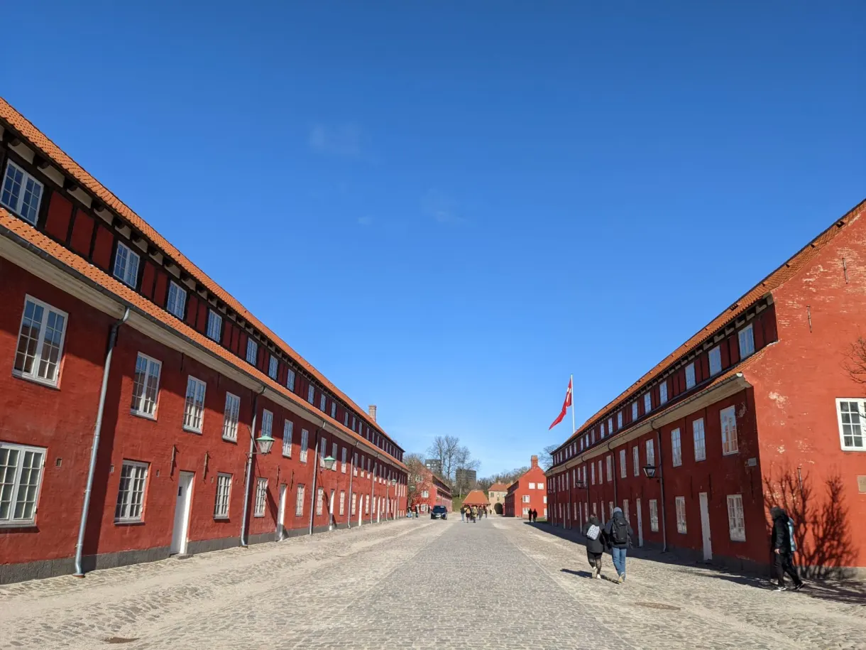 Longue allée pavée filant entre deux rangées de casernes rouges