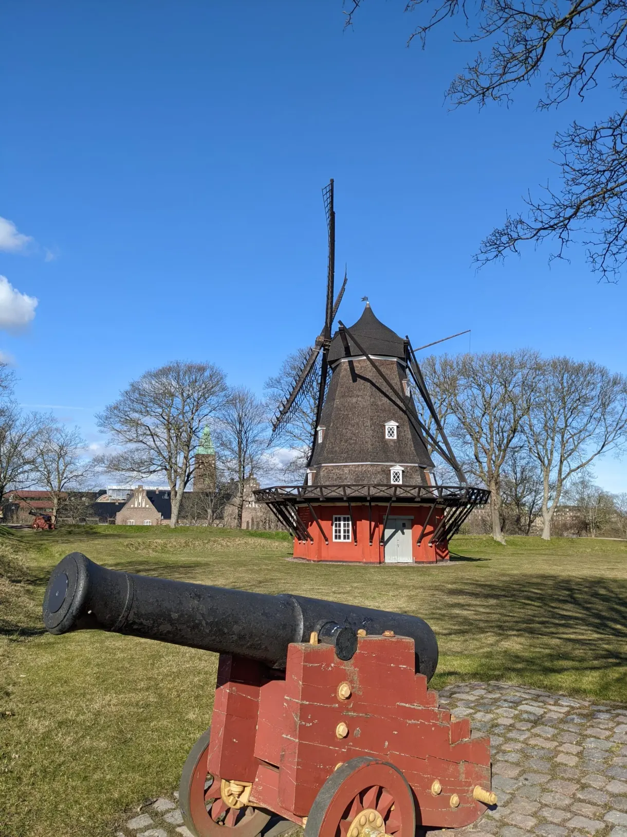 Vieux canon rouge braqué vers le moulin des remparts