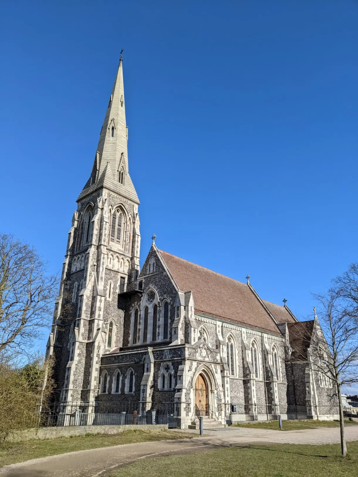 Église anglicane en pierre grise et sa flèche gothique effilée