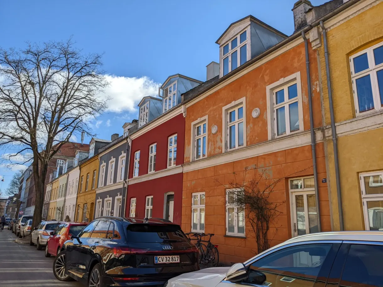 Rue résidentielle aux immeubles jaunes et rouges, arbres encore nus