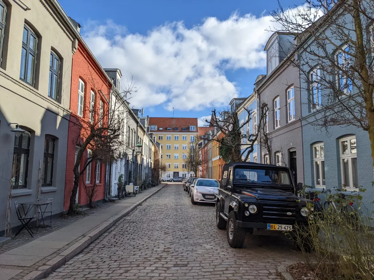 Rue pavée en pente douce entre maisons colorées, tout-terrain noir garé
