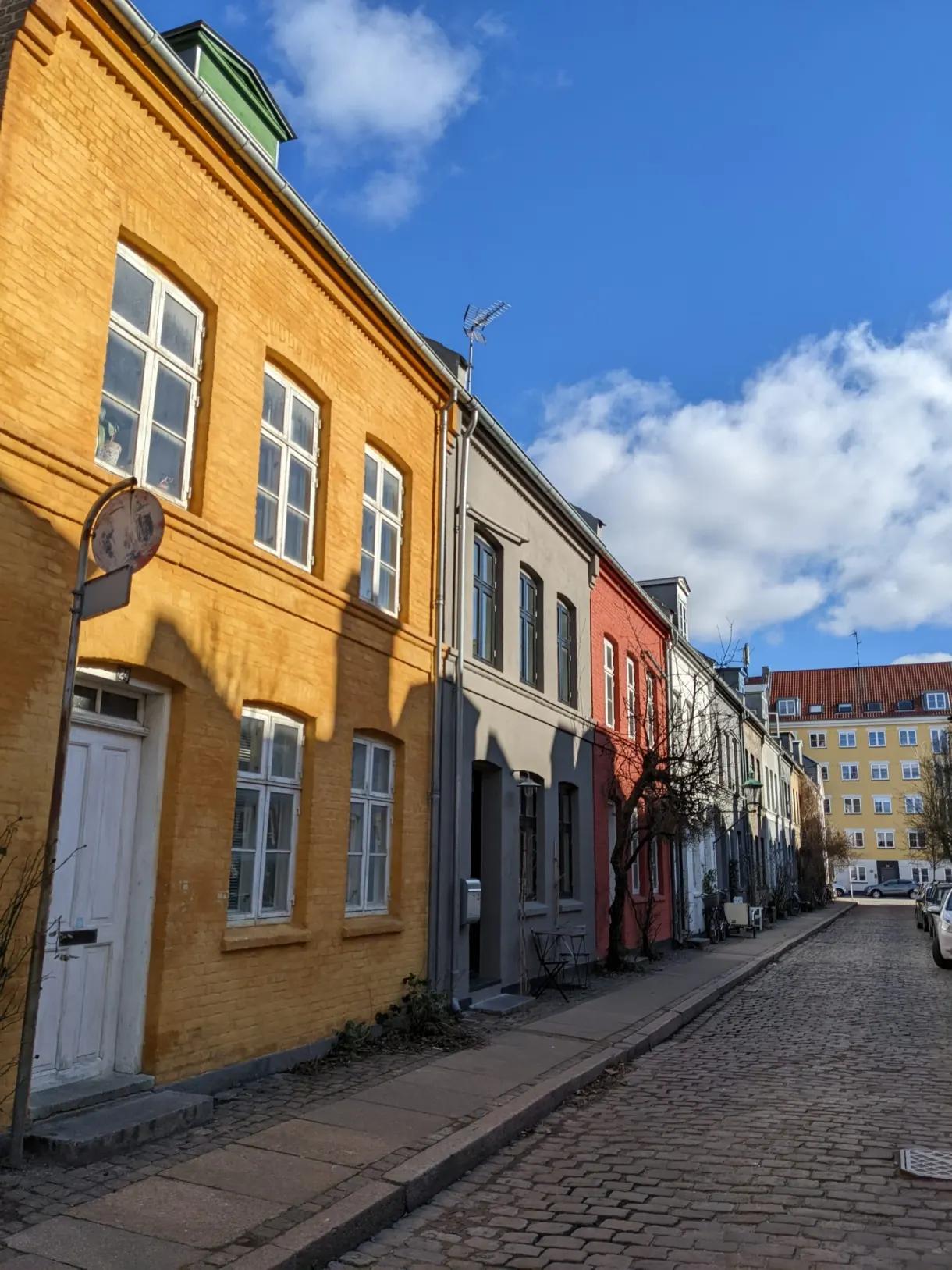 Façade jaune vif ouvrant sur une ruelle pavée aux maisons contrastées