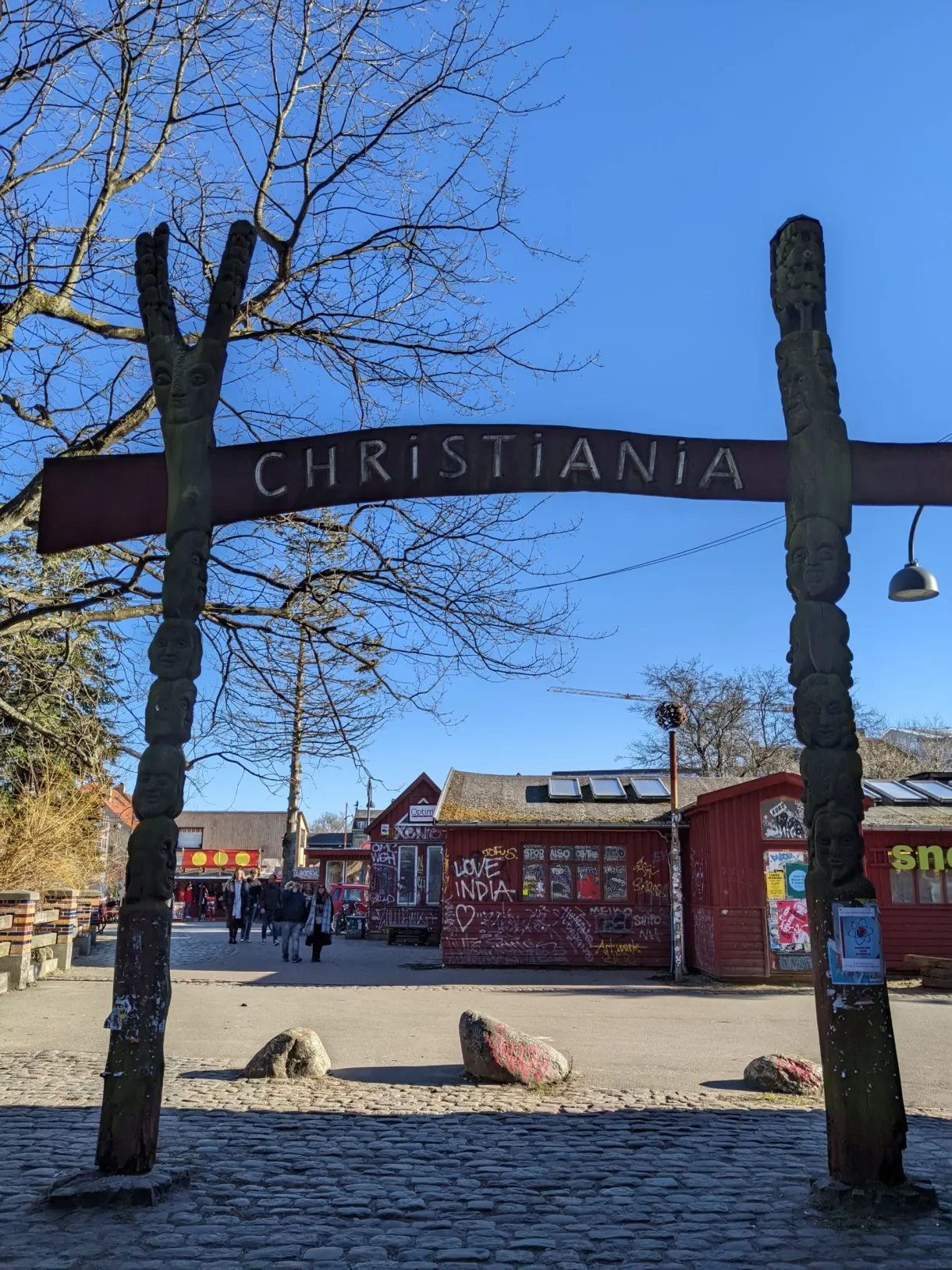 Portique de bois marqué Christiania entre deux totems sculptés