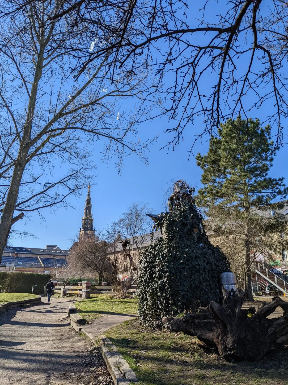 Sentier arboré au bord de l'eau, flèche d'église au loin