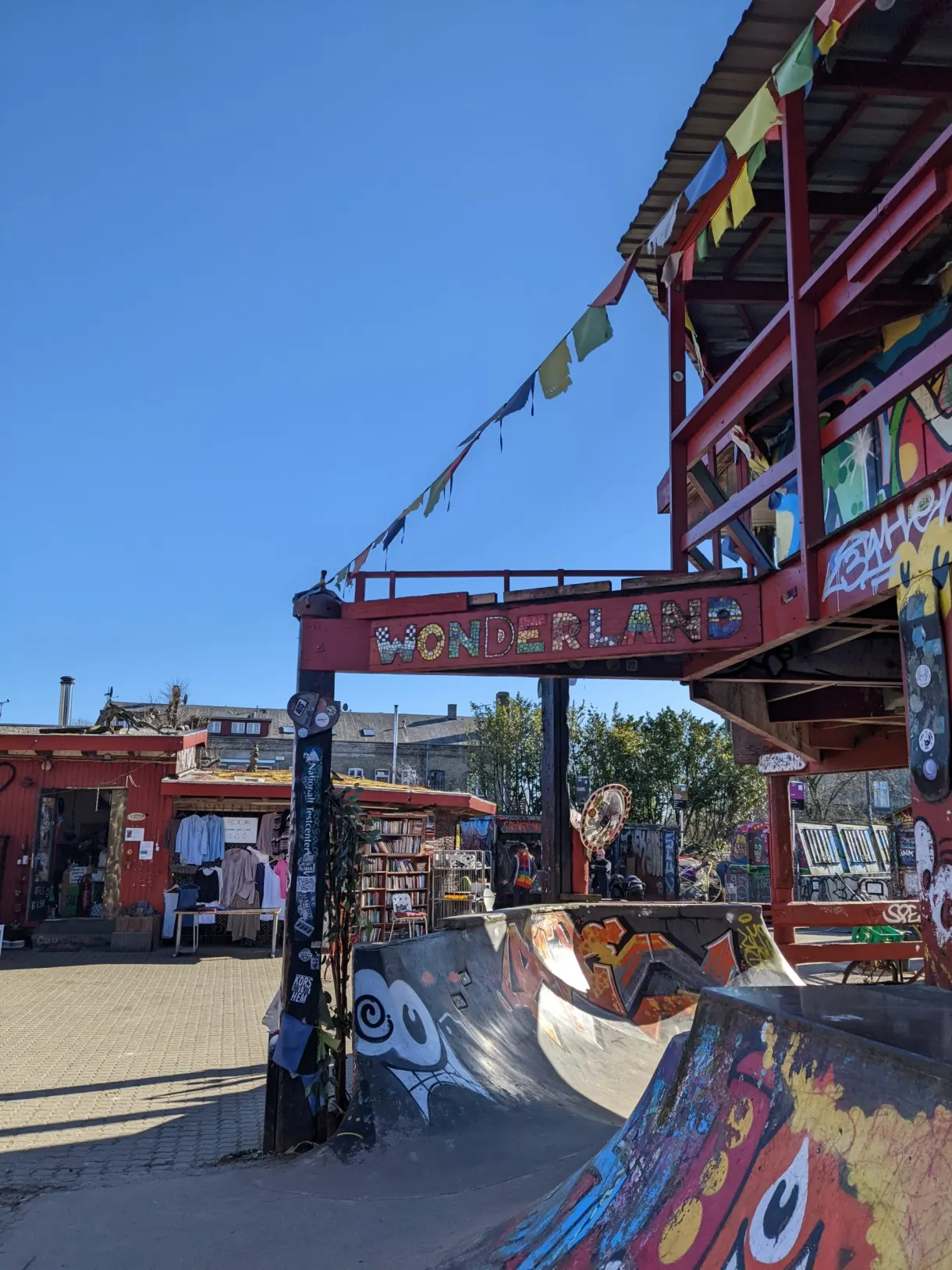 Portail bariolé et drapeaux de prières au-dessus d'un skatepark peint