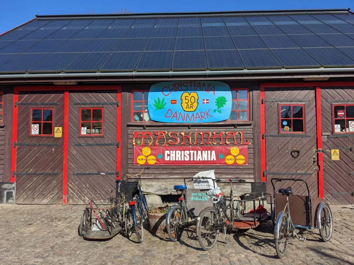 Hangar de bois brun à l'enseigne peinte, vélos cargo garés devant