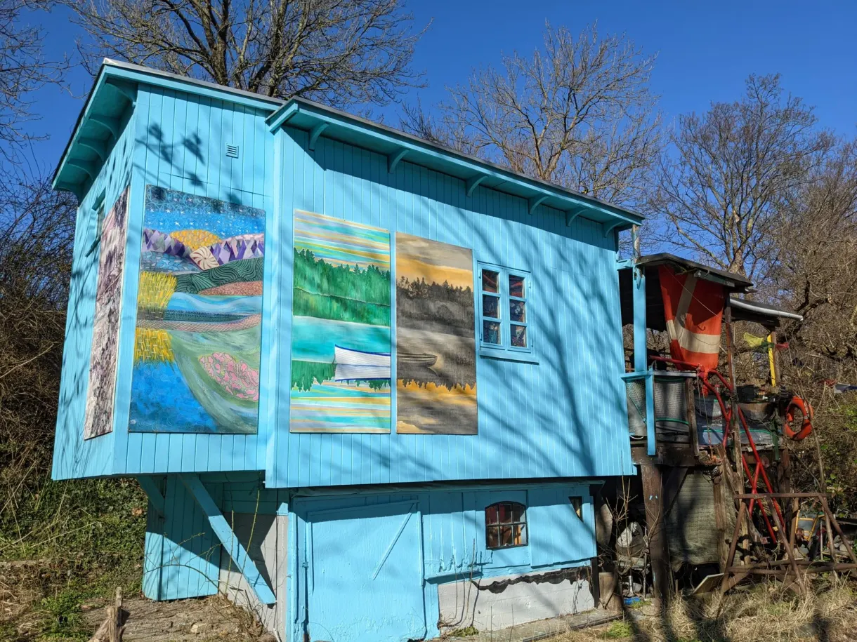 Cabane turquoise sur pilotis décorée de tableaux peints