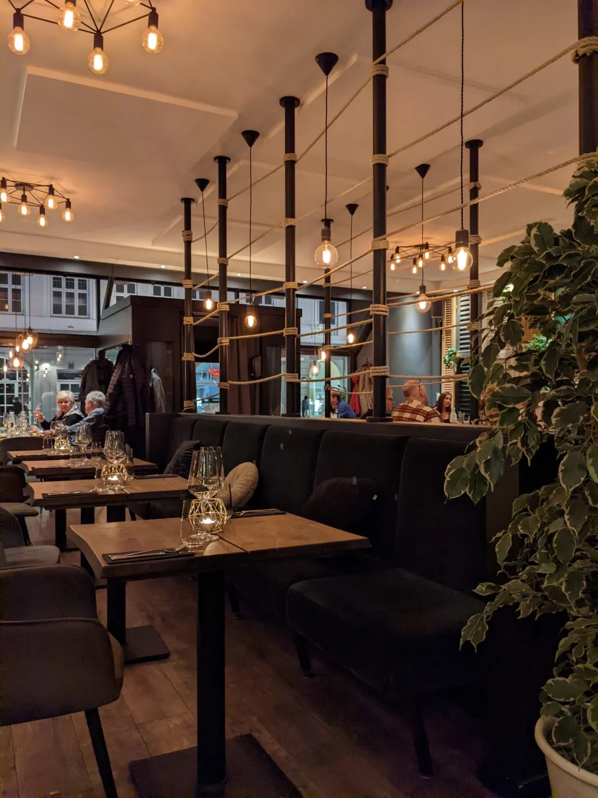 Salle de restaurant aux ampoules suspendues et banquettes sombres
