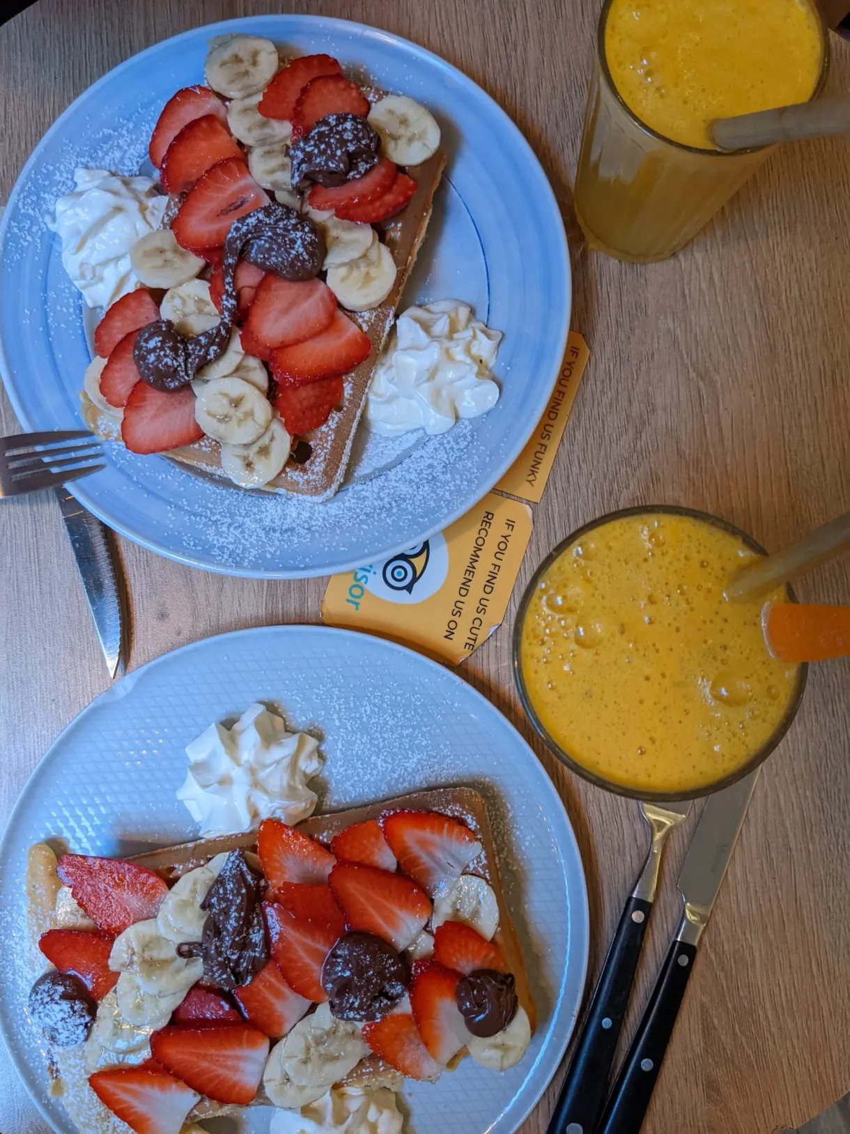 Deux assiettes de gaufres aux fraises et verres de jus d'orange