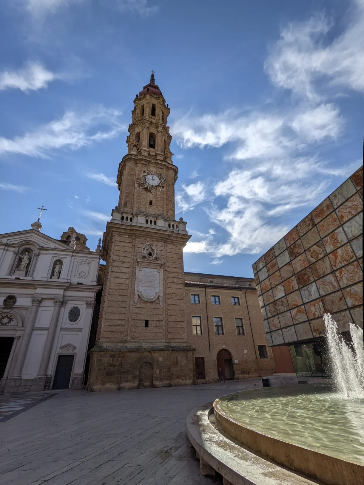 Bell tower of La Seo and fountain in front of a glass pyramid