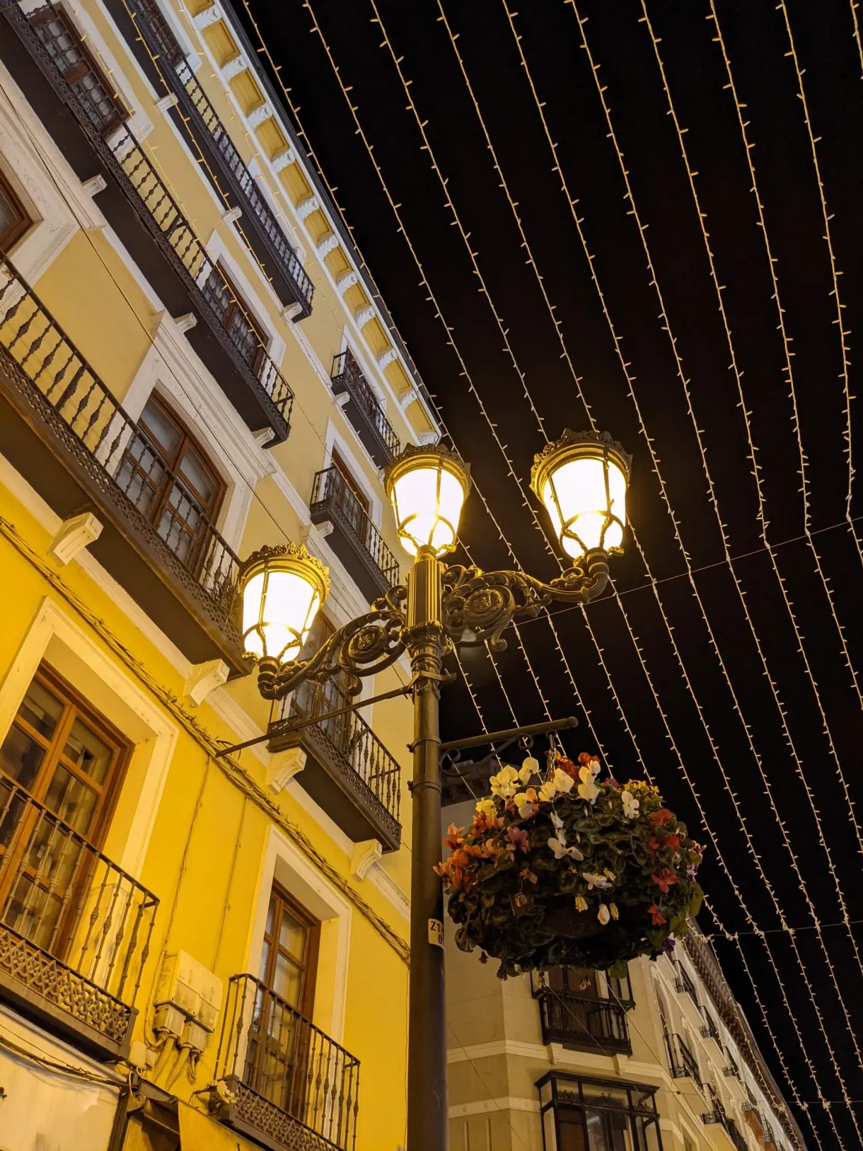 Street lamps and garlands above a yellow facade