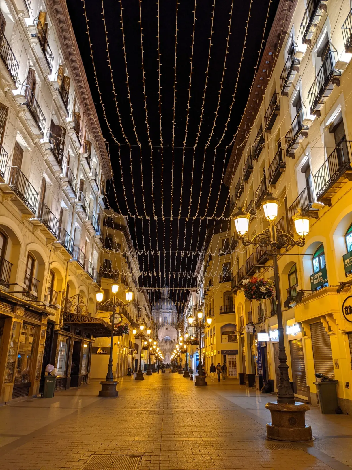 Shopping street lit by a canopy of garlands