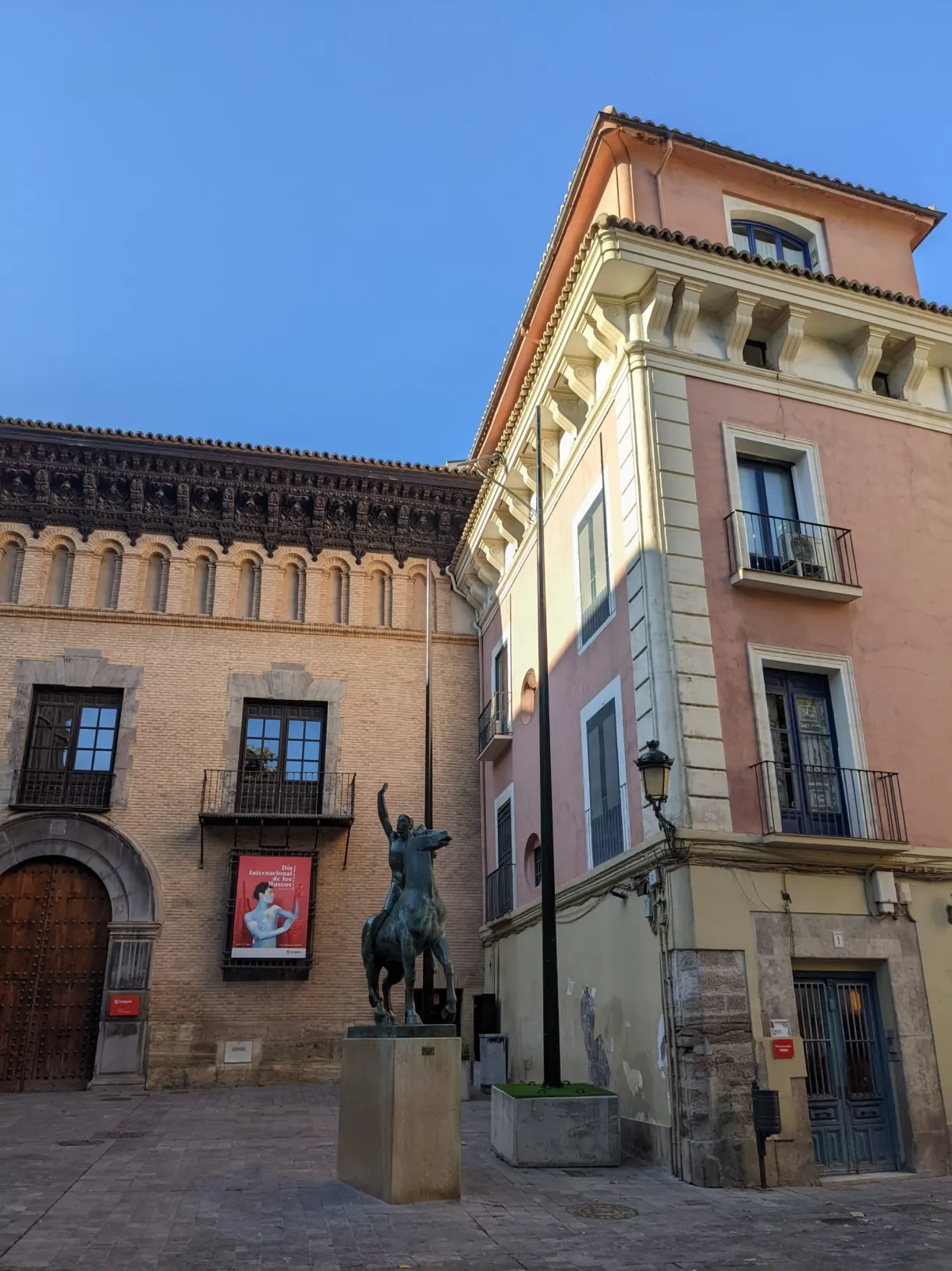 Equestrian statue in front of pink and ochre facades