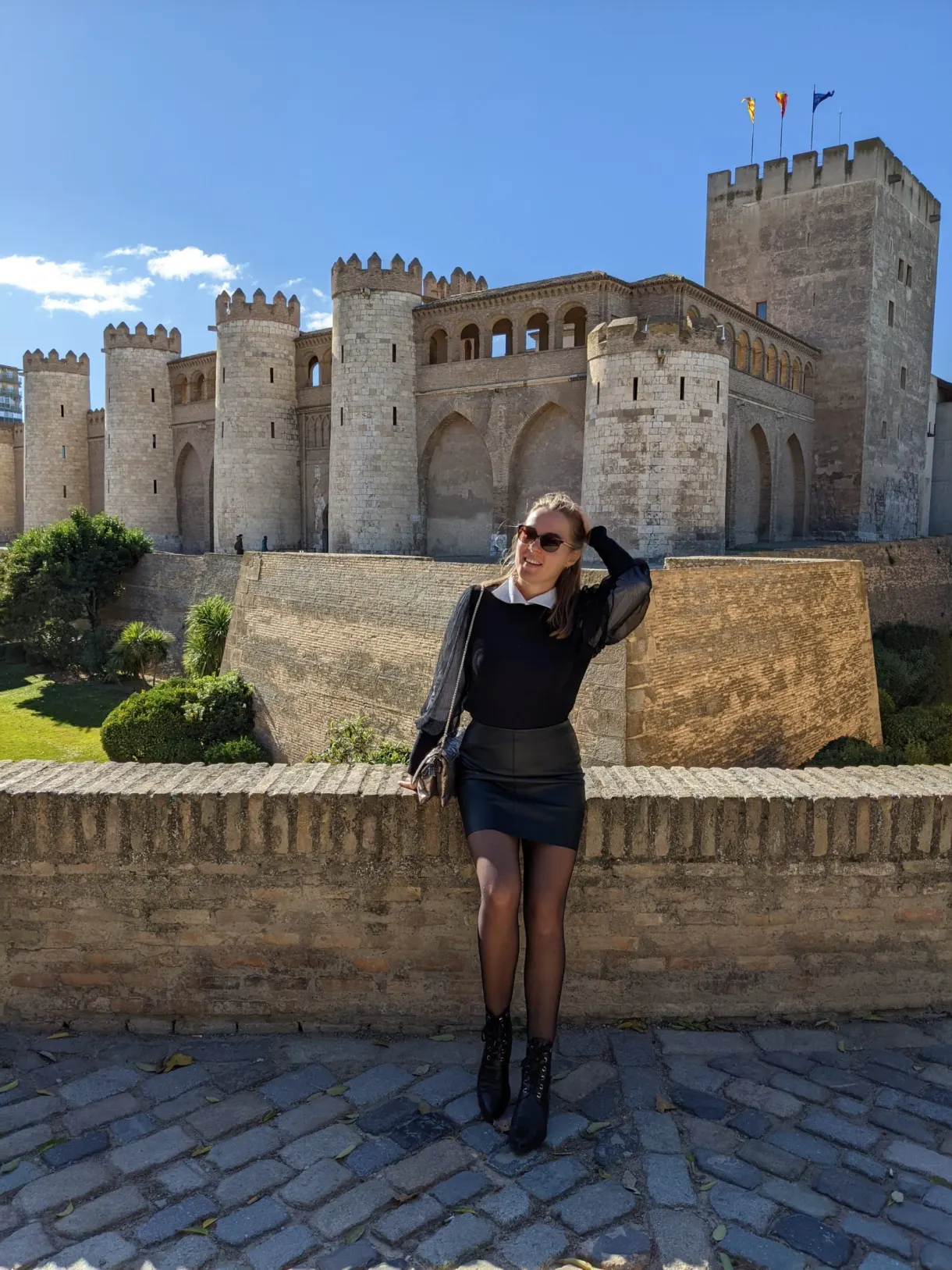 Woman leaning on a low wall facing the fortified palace