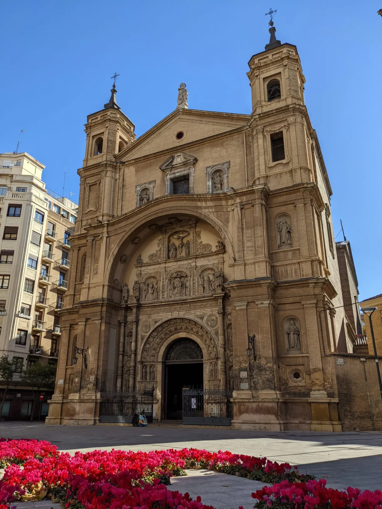 Baroque church in front of a bed of red flowers