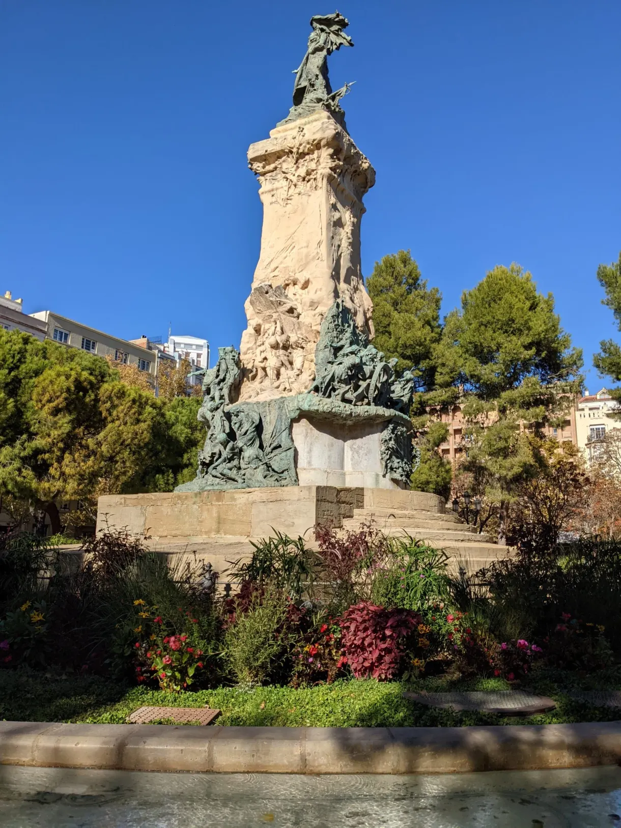 Carved monument in the middle of a flowering garden