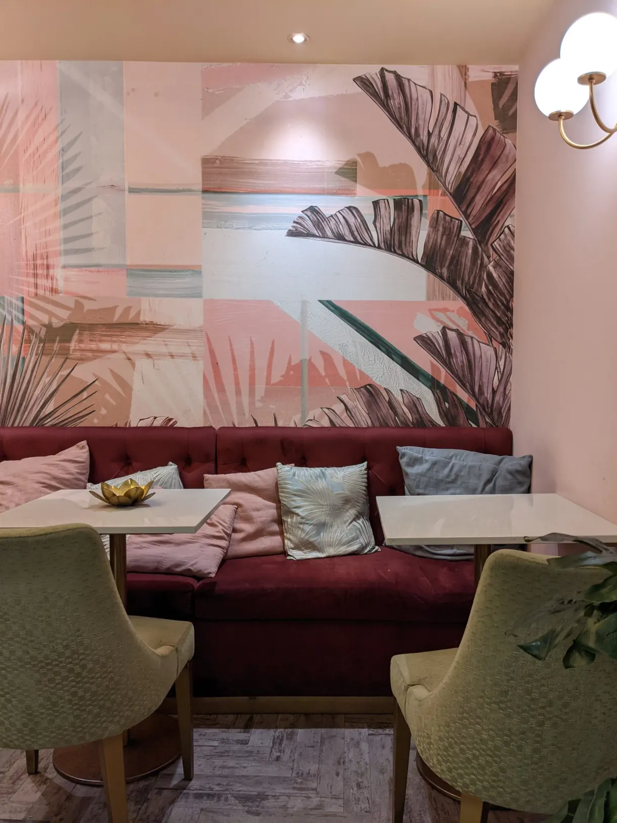 Burgundy banquette and pink walls of a restaurant dining room