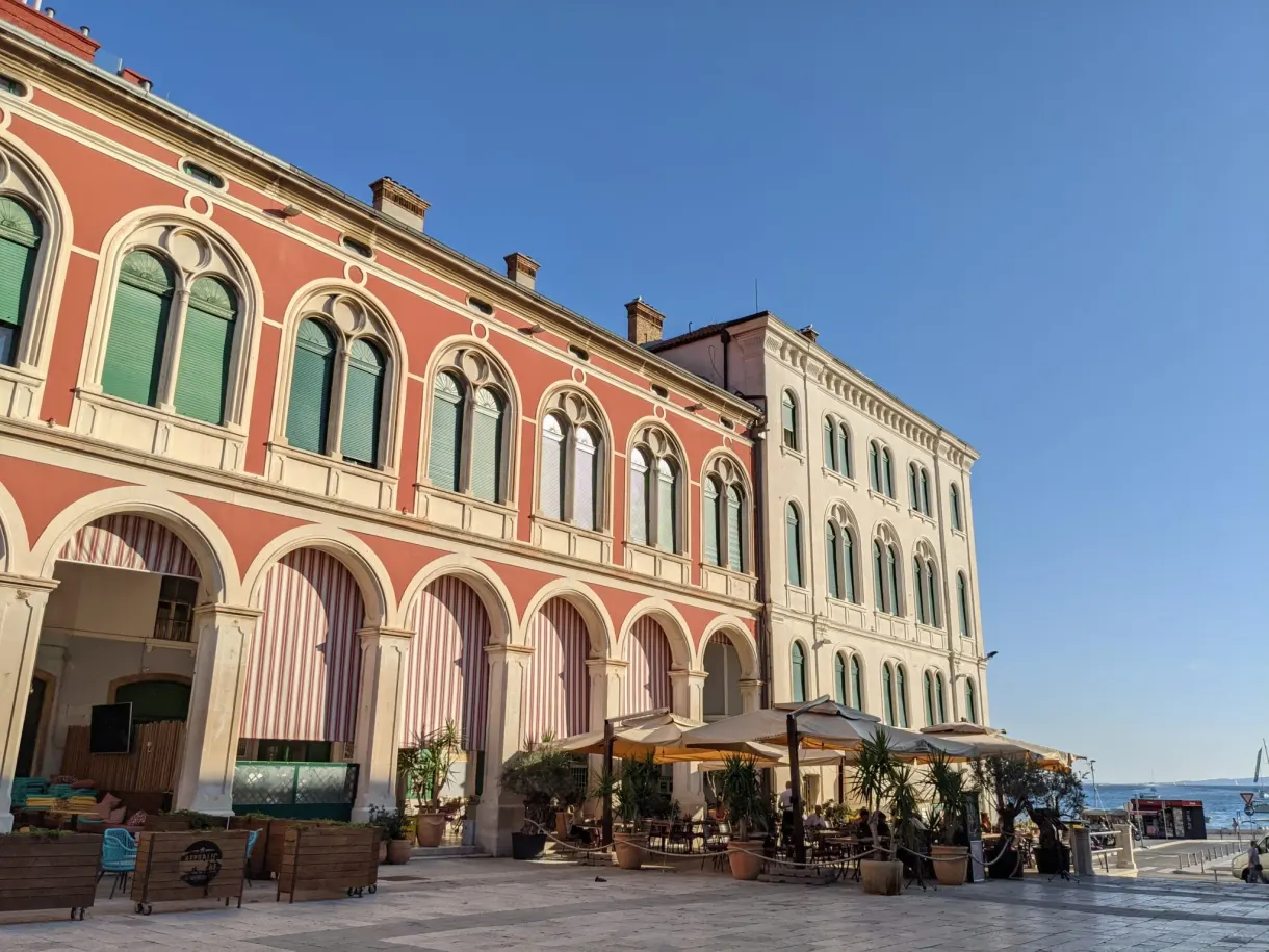 Red arcaded facade and cafe terraces by the sea