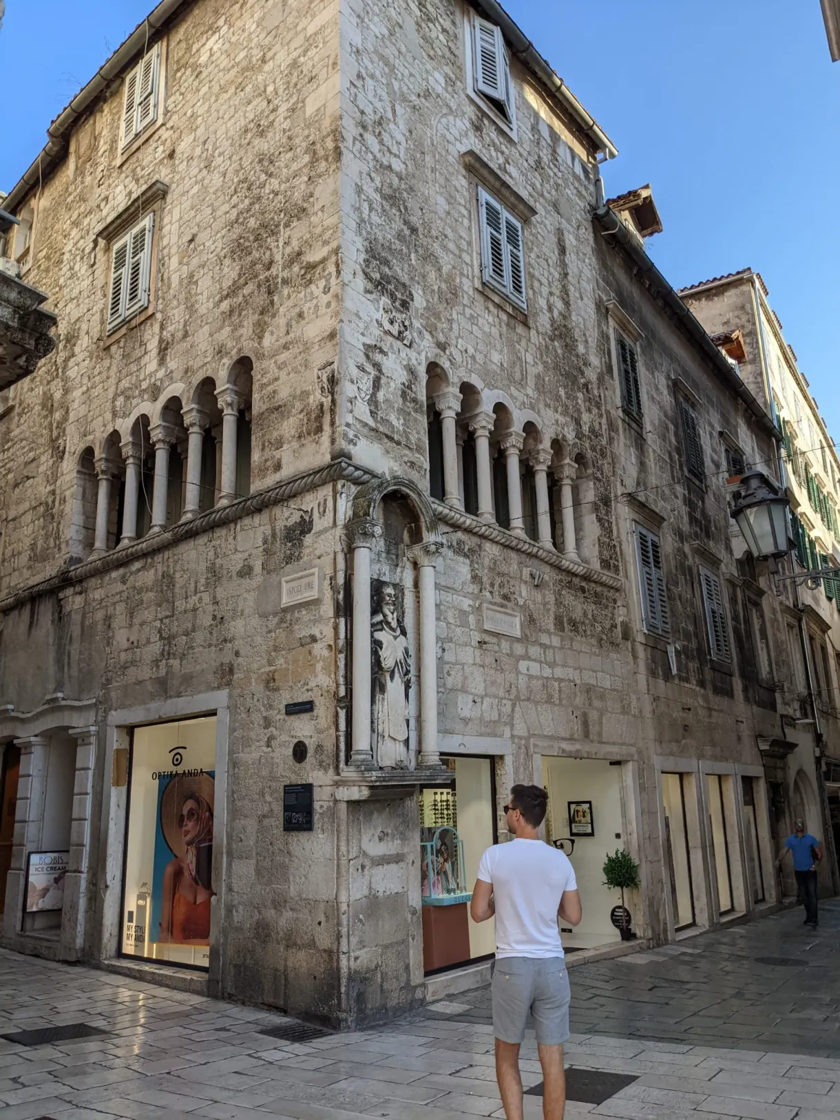 Corner of a white stone building with shop windows at street level