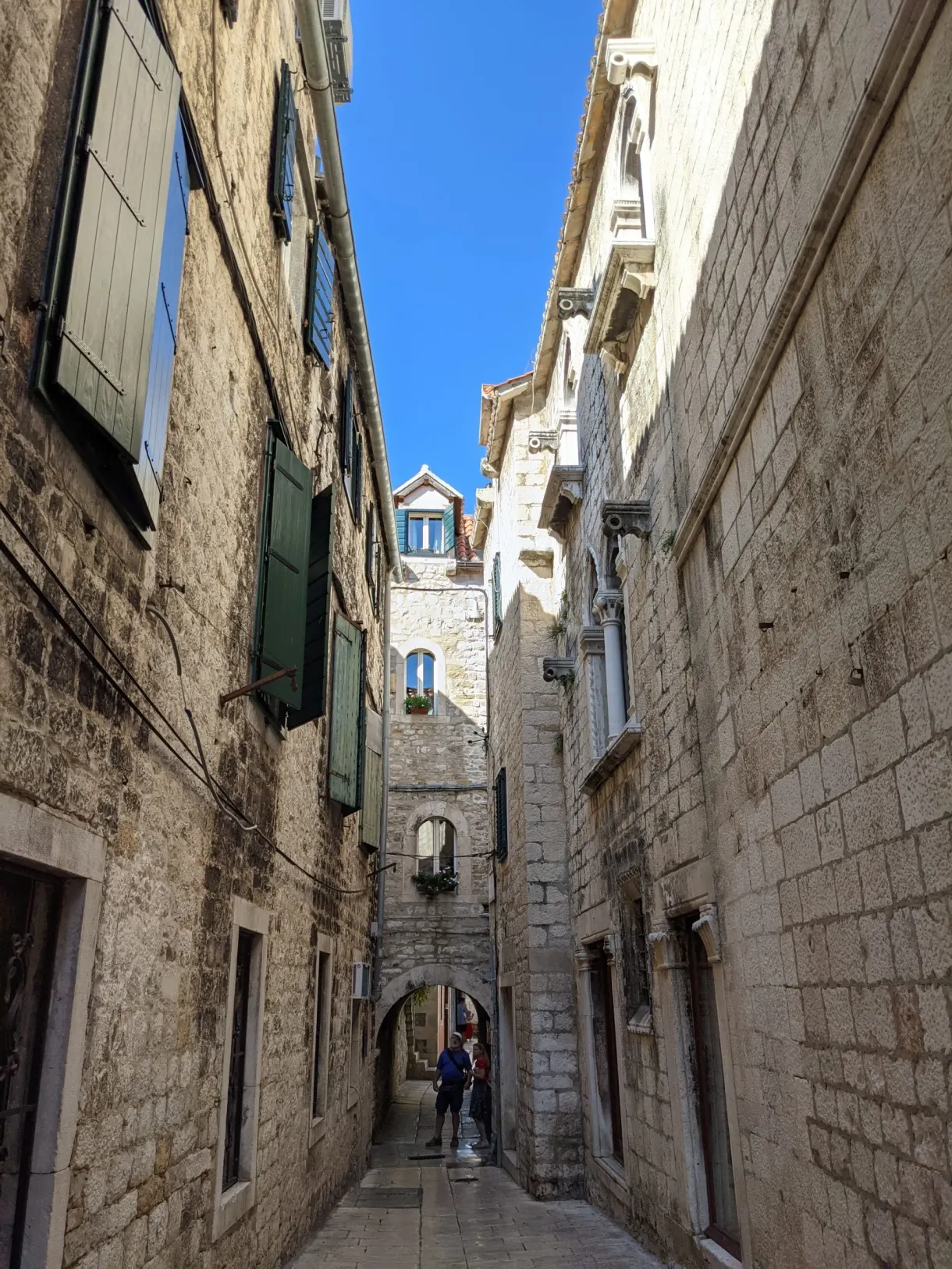 Narrow lane with high stone walls and green shutters