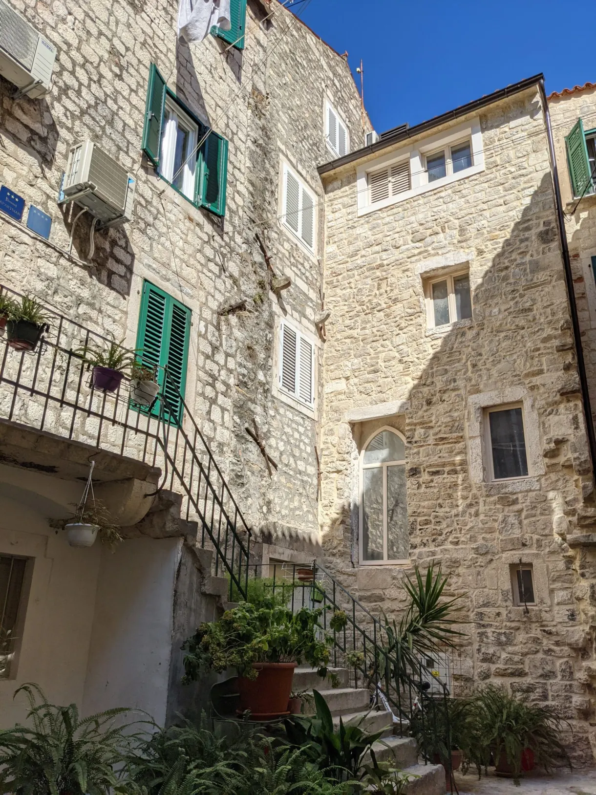Stone courtyard with an outside staircase and potted plants