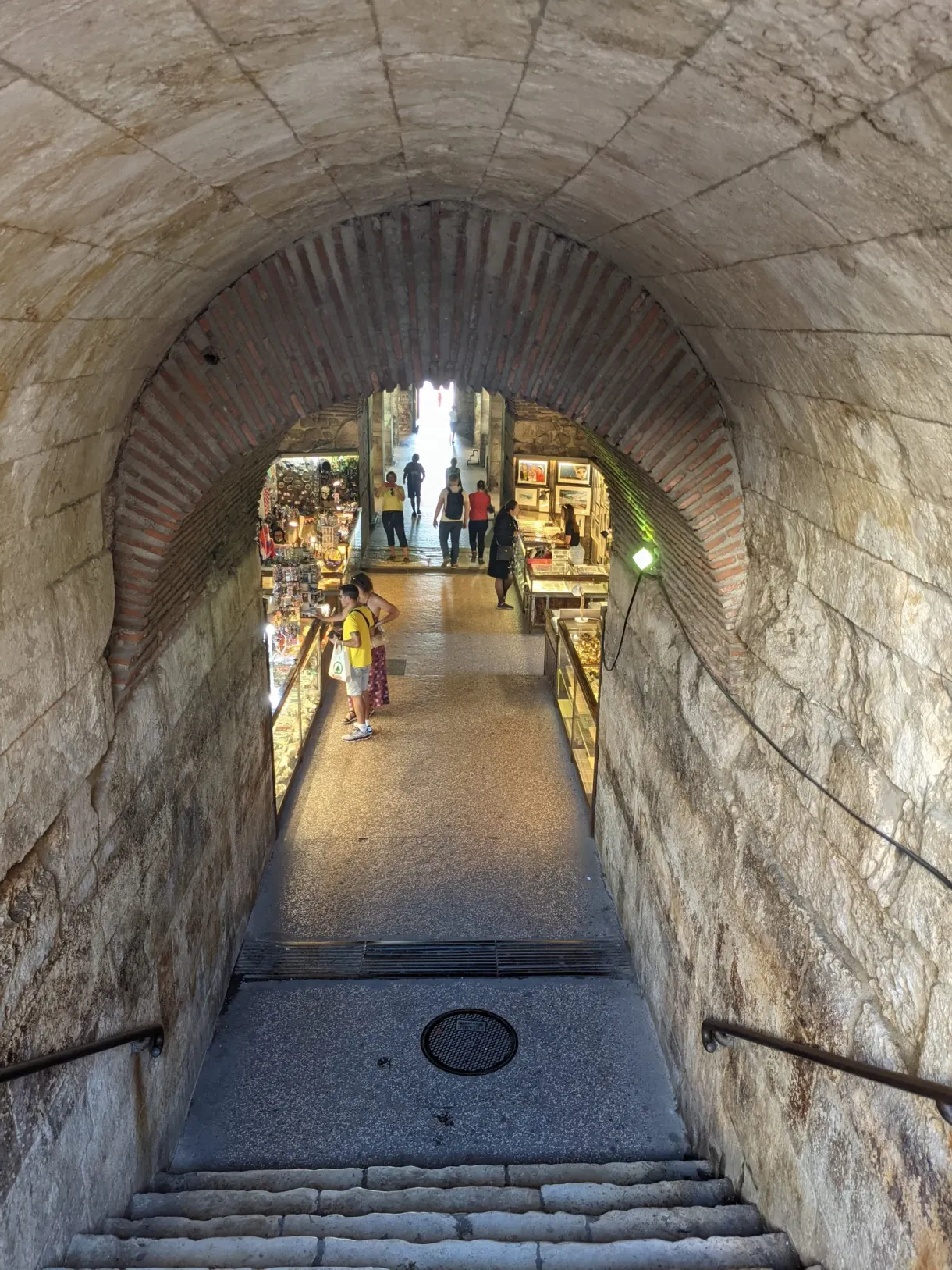 Vaulted passage and staircase leading down to lit stalls
