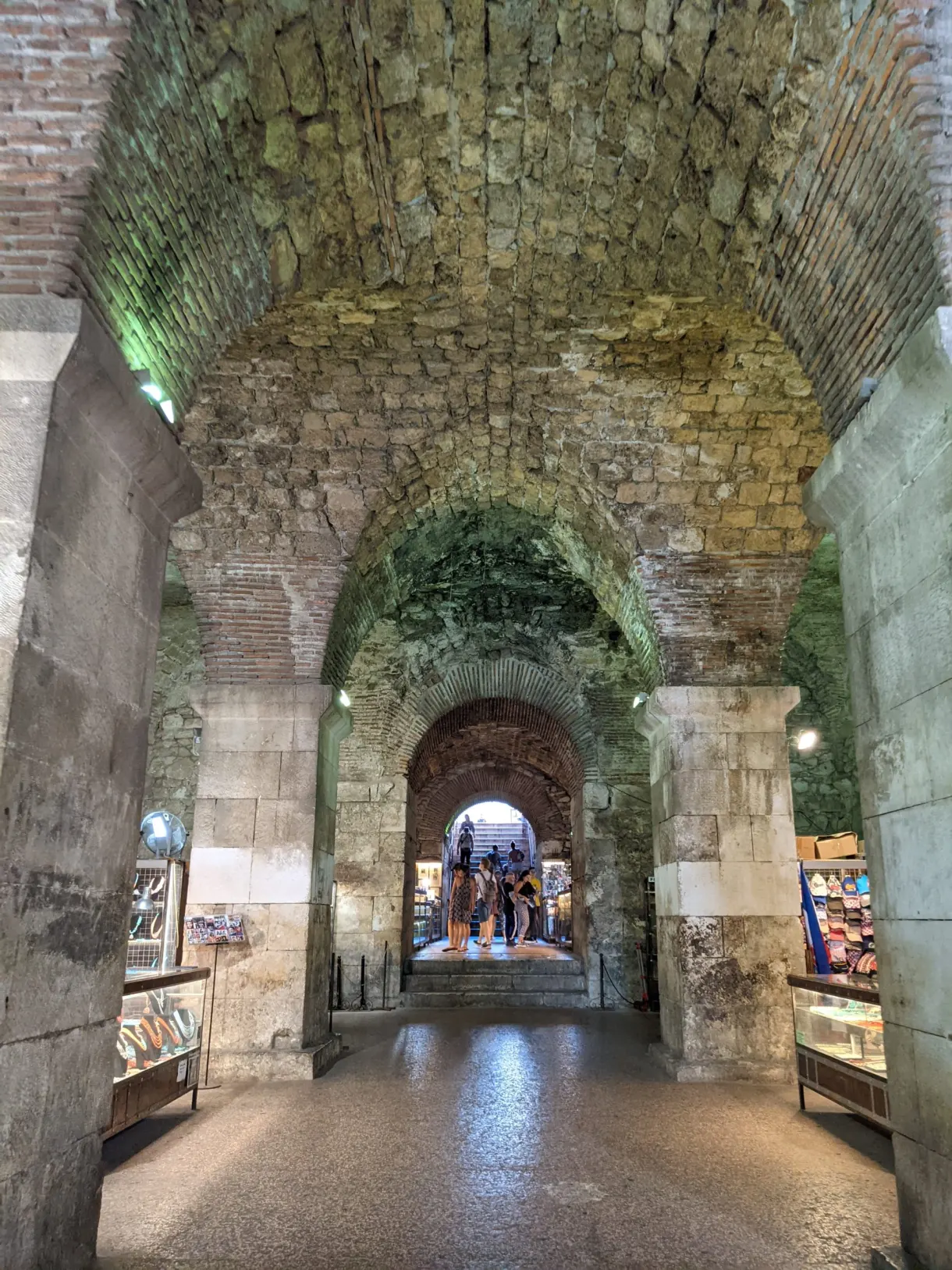 Lit vaulted cellars with shops and an arch at the far end