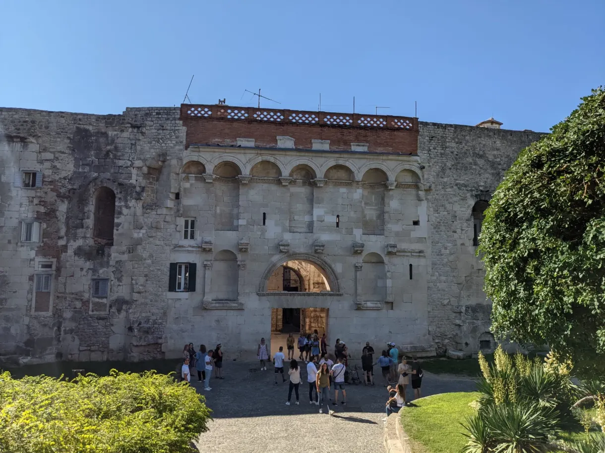 Arcaded facade of the palace and visitors on the esplanade