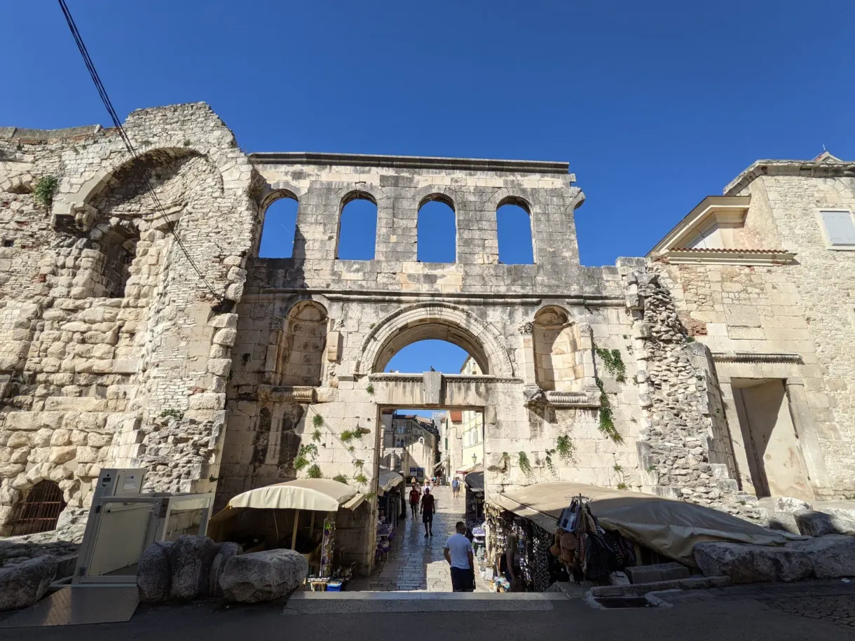 Ruined Roman gate and stalls set up at the foot of the arcades
