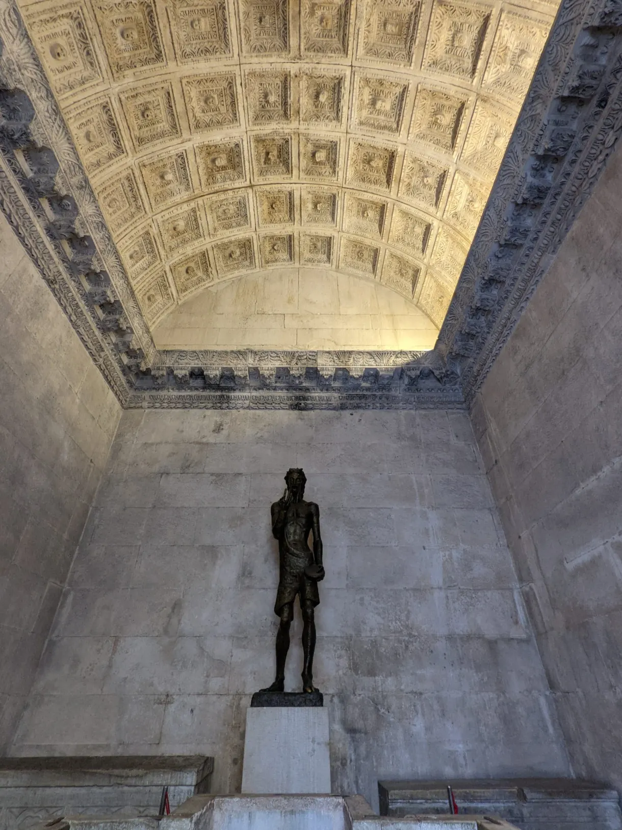 Bronze statue beneath a carved coffered ceiling