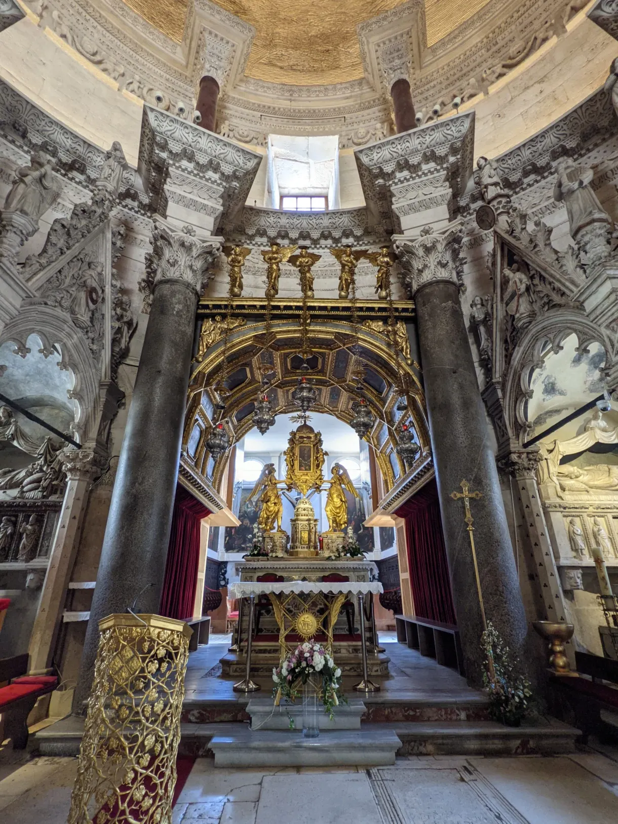 Gilded baroque altar beneath the columns of a chapel