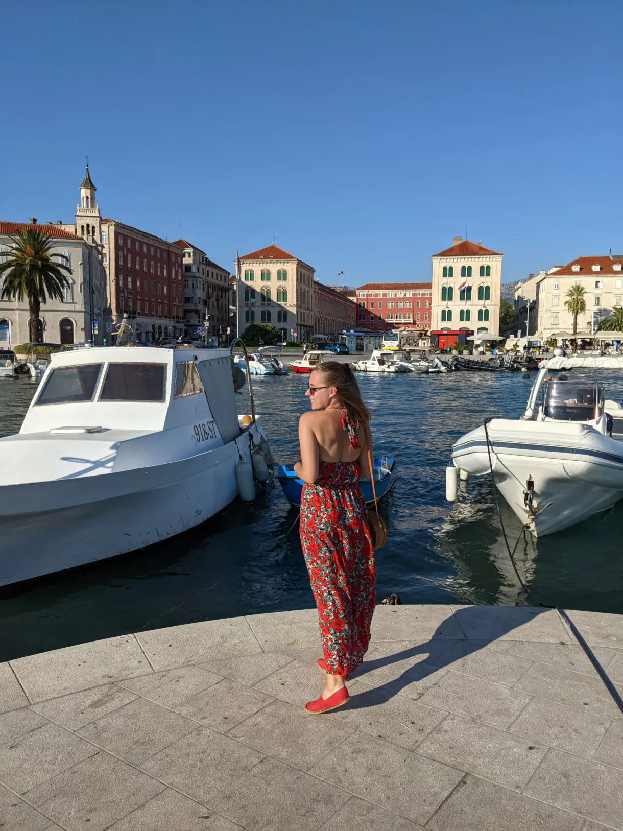 Woman in a red dress between two moored boats