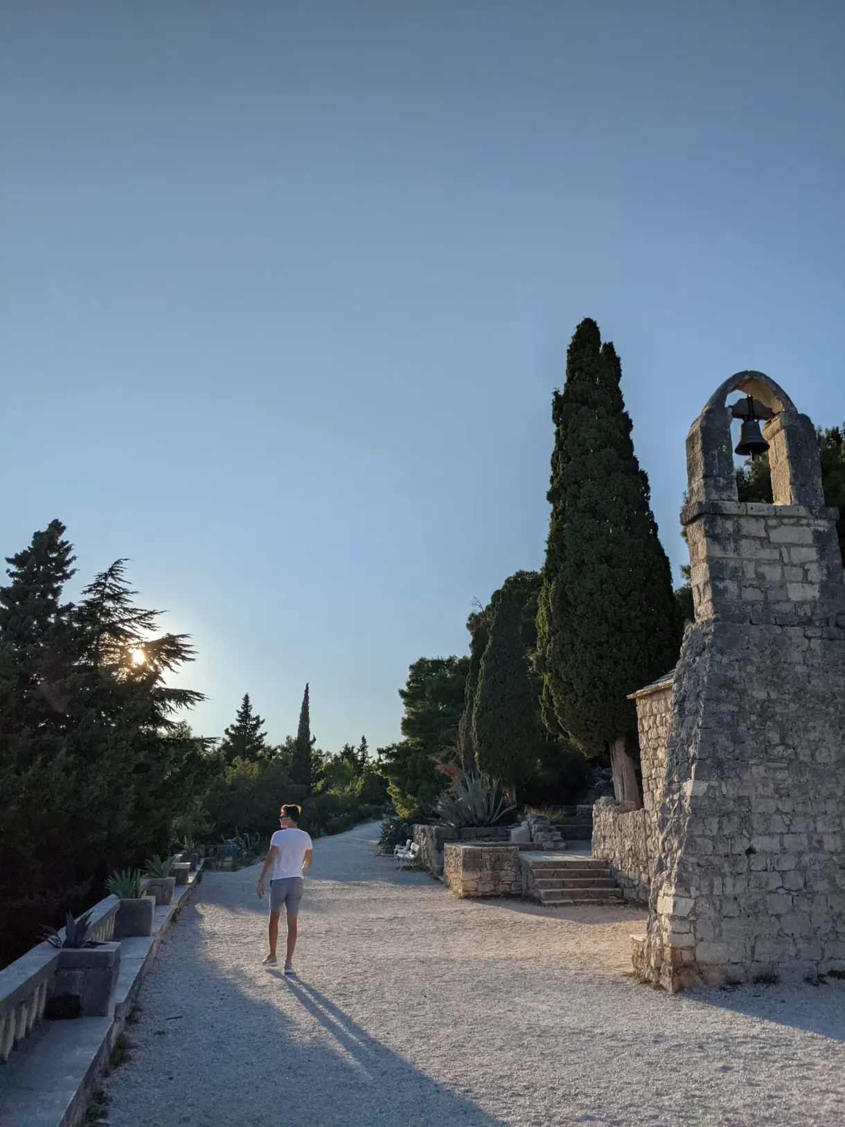 Gravel path leading to a stone chapel among the cypresses