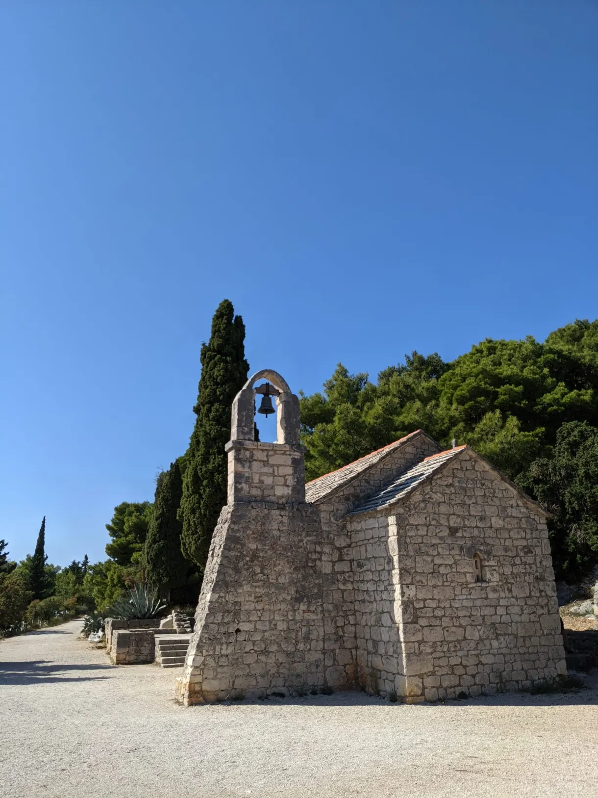 White chapel with a bell turret at the end of a gravel path