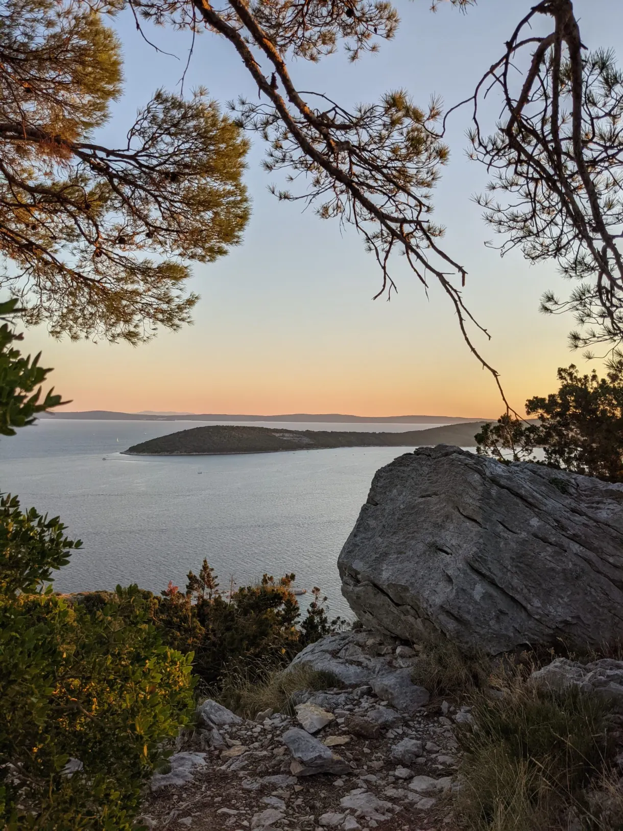 Large rock on the ridge, islands on the horizon at sunset
