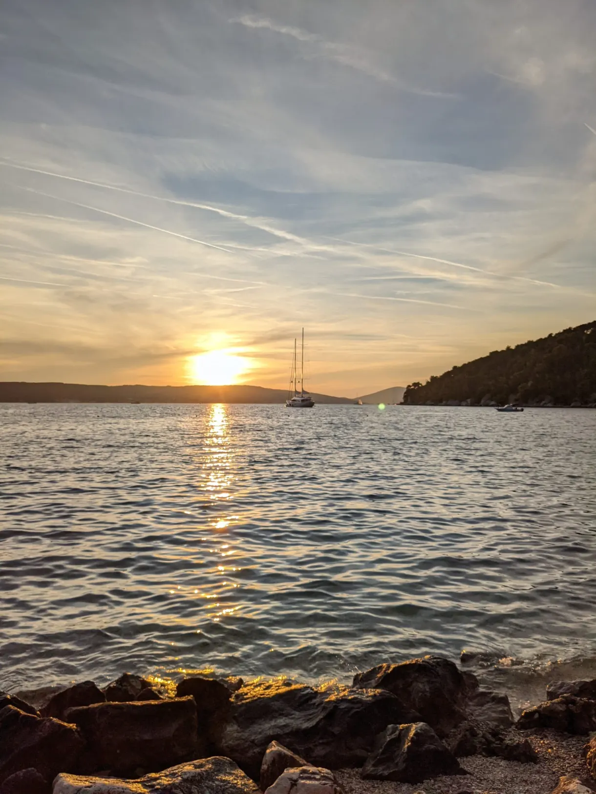Sun setting over the sea, dark rocks in the foreground