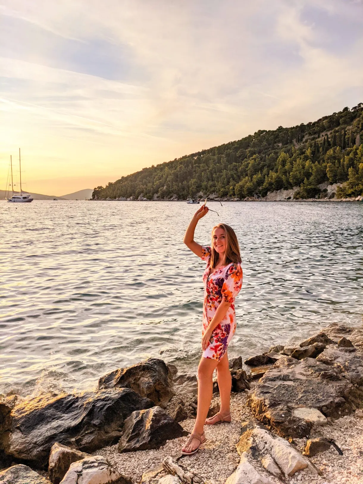 Woman in a floral dress standing on the rocks by the shore