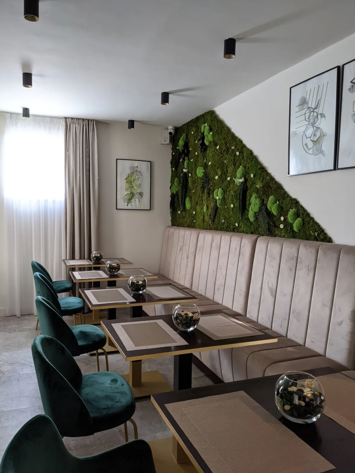 Breakfast room with green armchairs and a plant wall