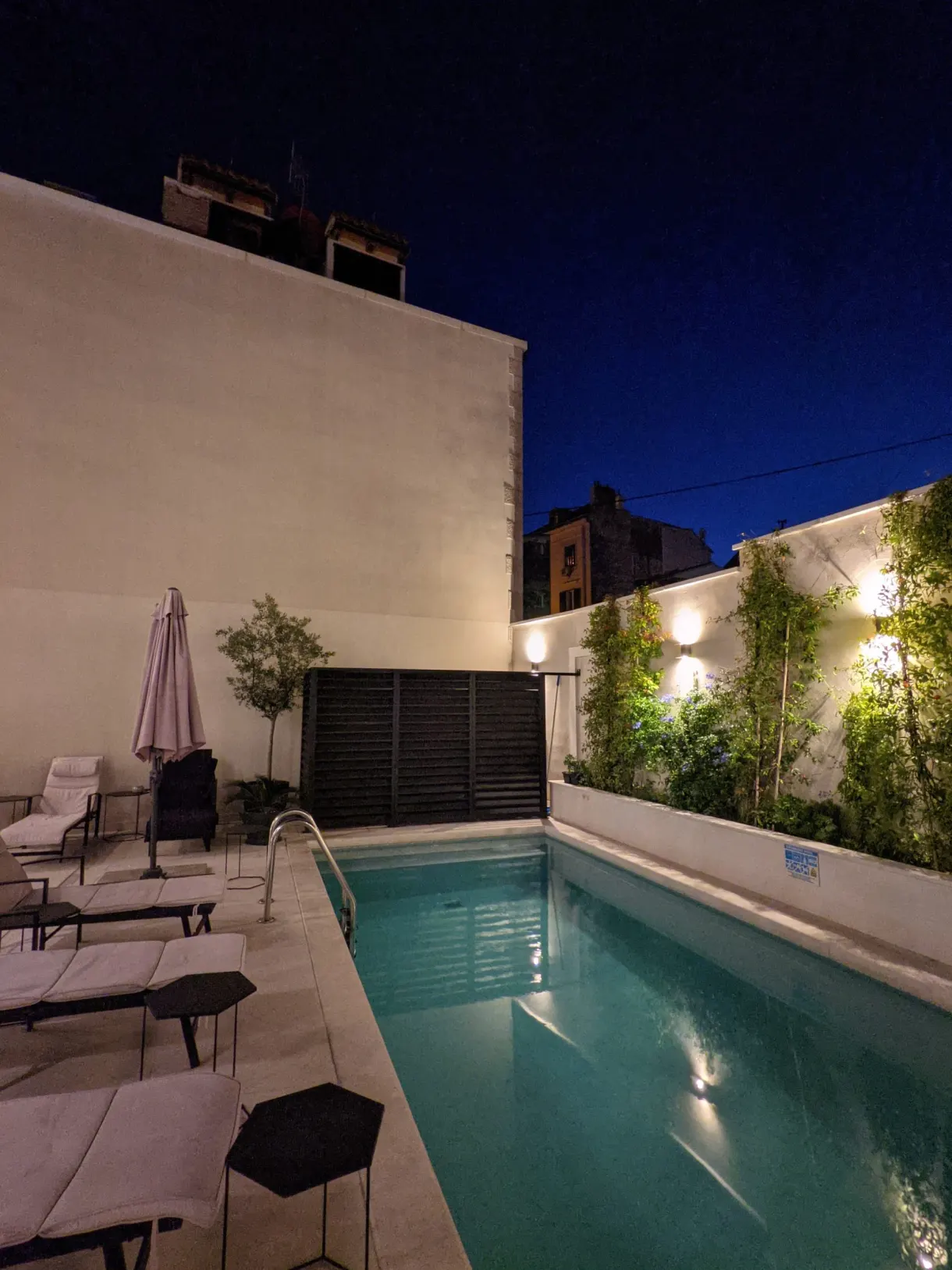 Lit swimming pool in an enclosed courtyard after dark