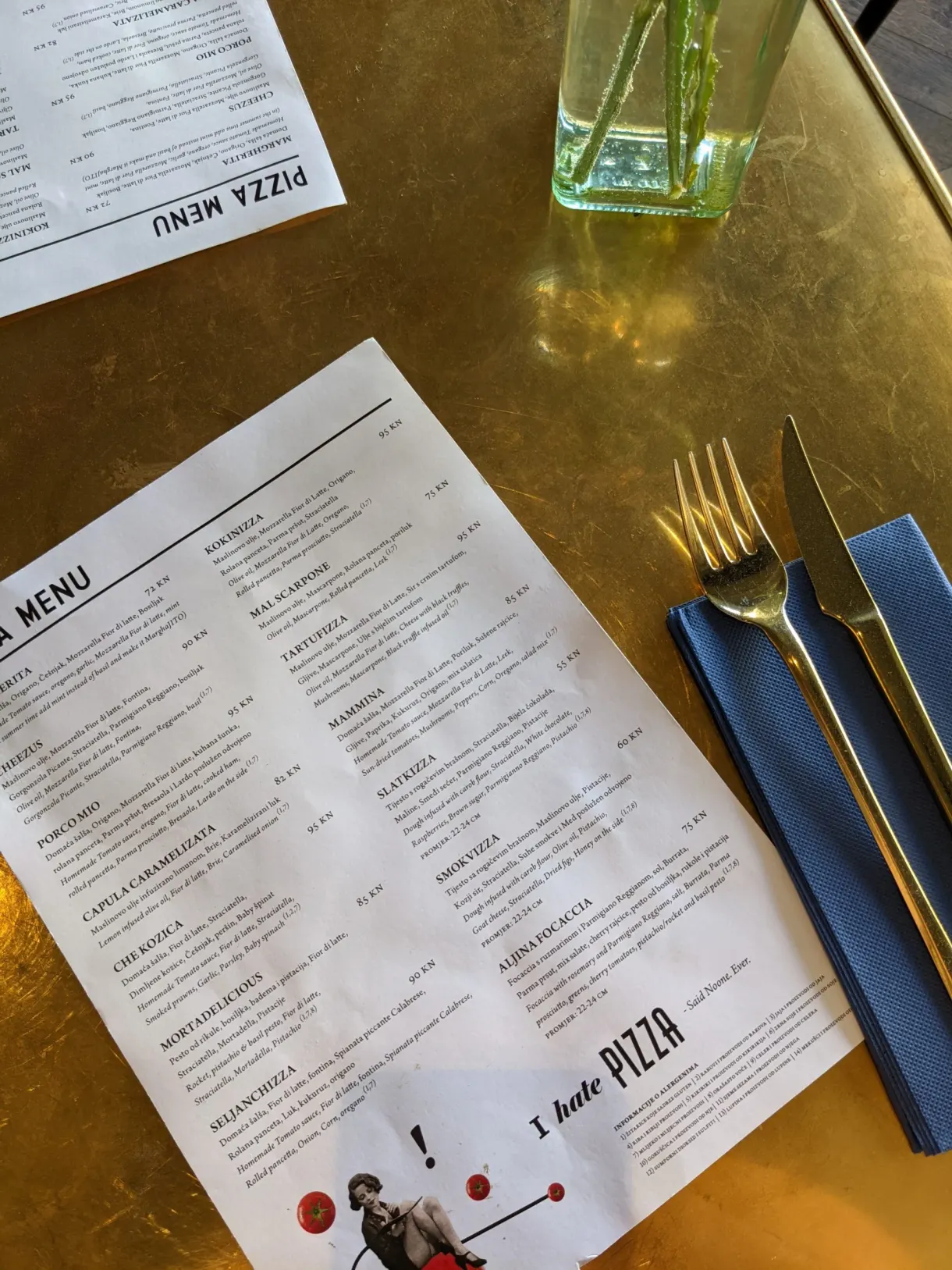 Pizzeria menu on a golden table with cutlery