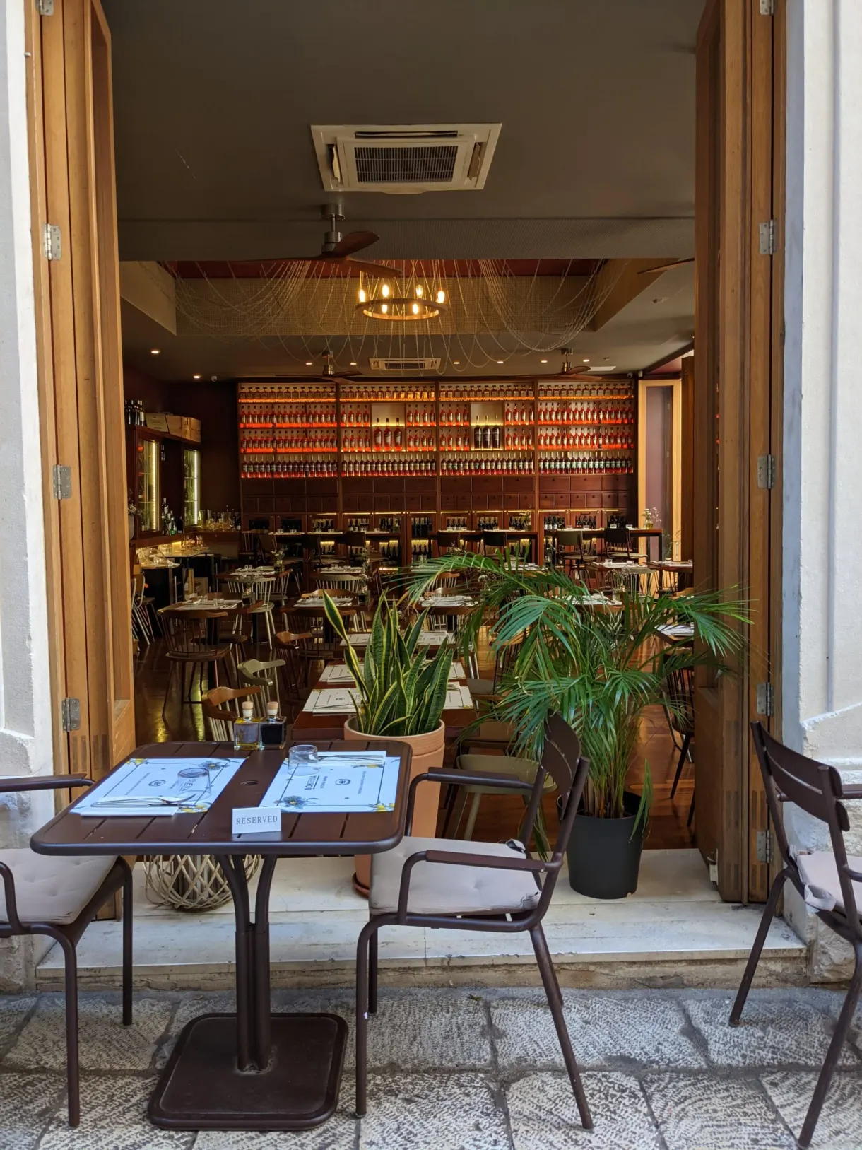 Open front of a bar with tables and green plants