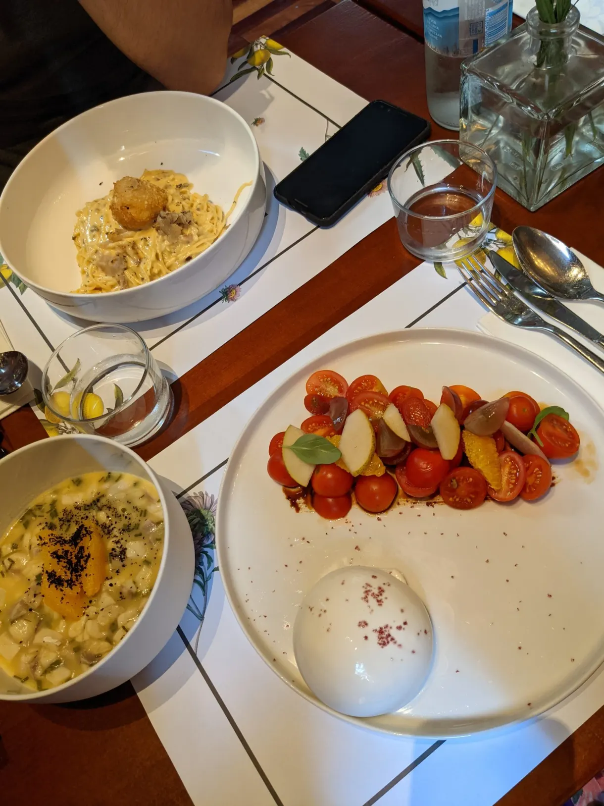 Plates of pasta and tomato salad on a laid table