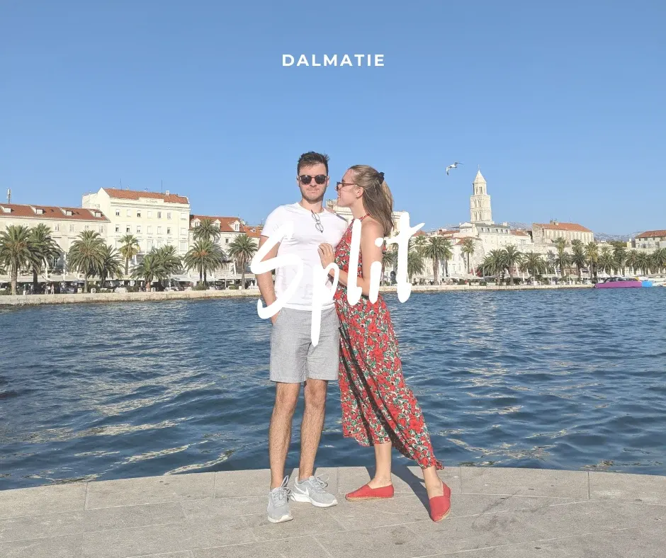 Couple posing at the water's edge in front of the old town