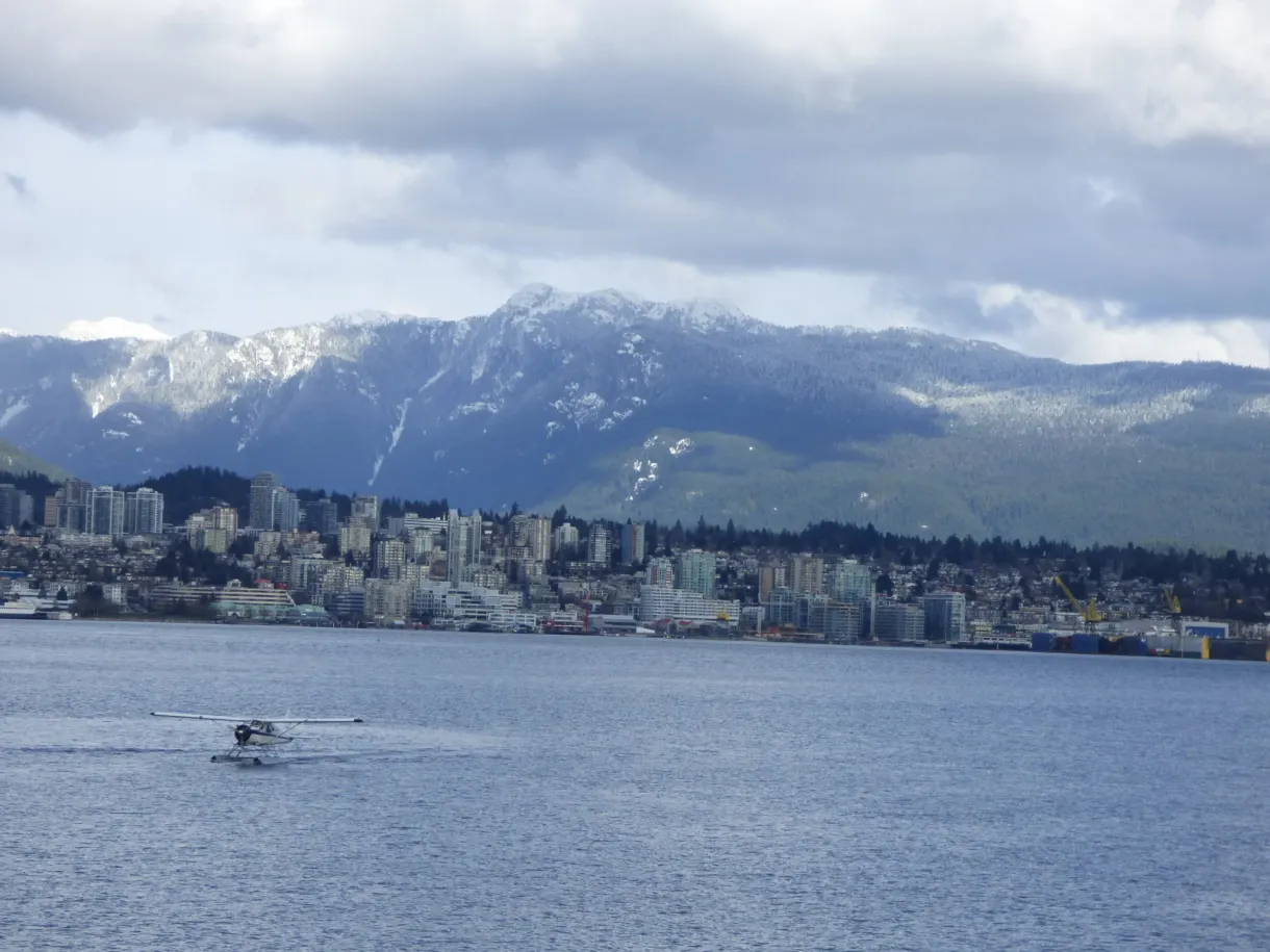 Seaplane gliding in front of the snow-capped mountains of the north shore