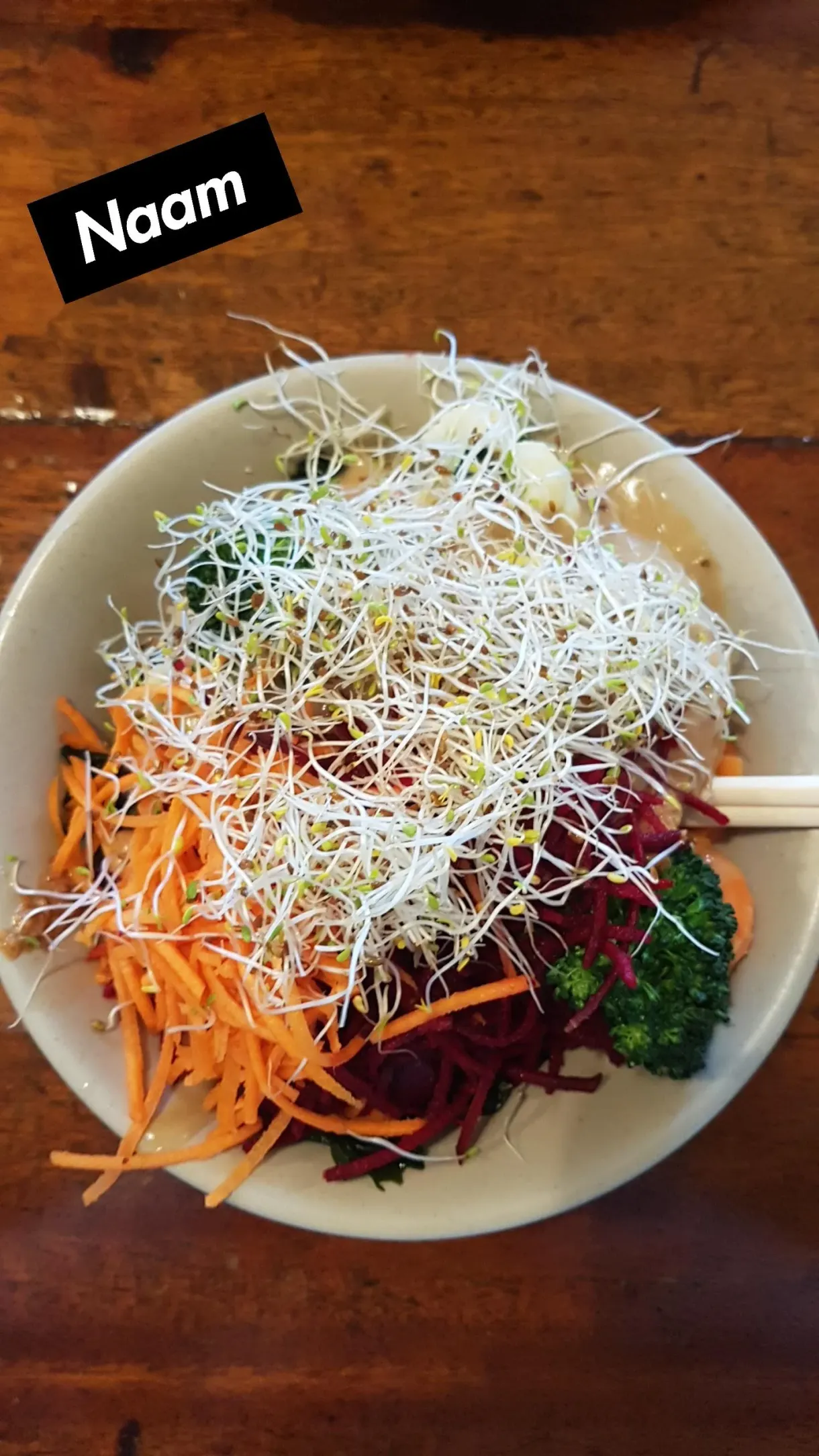 Bowl of raw vegetables with sprouts, grated carrot and beetroot