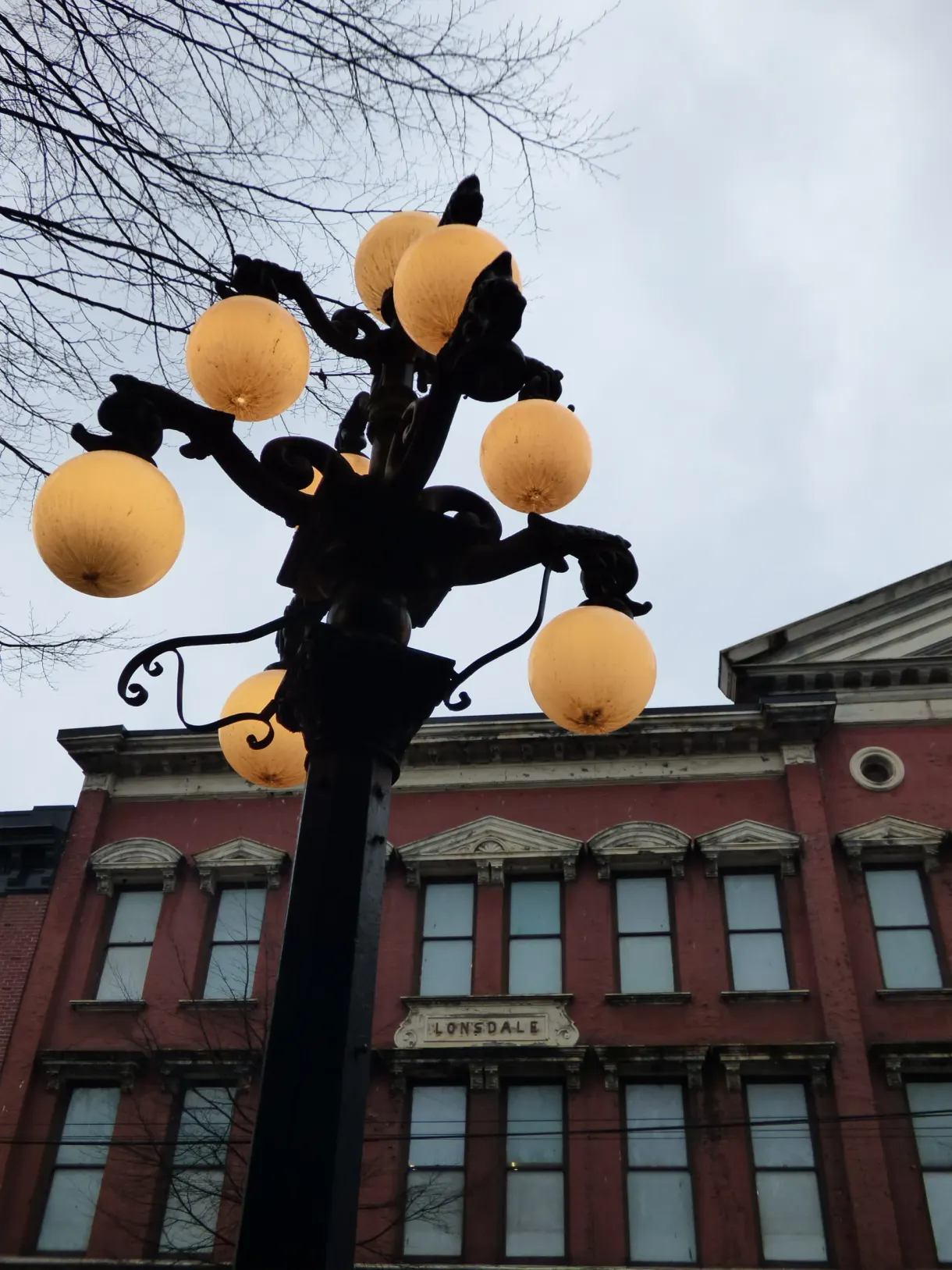 Lamp post with amber globes in front of a brick façade