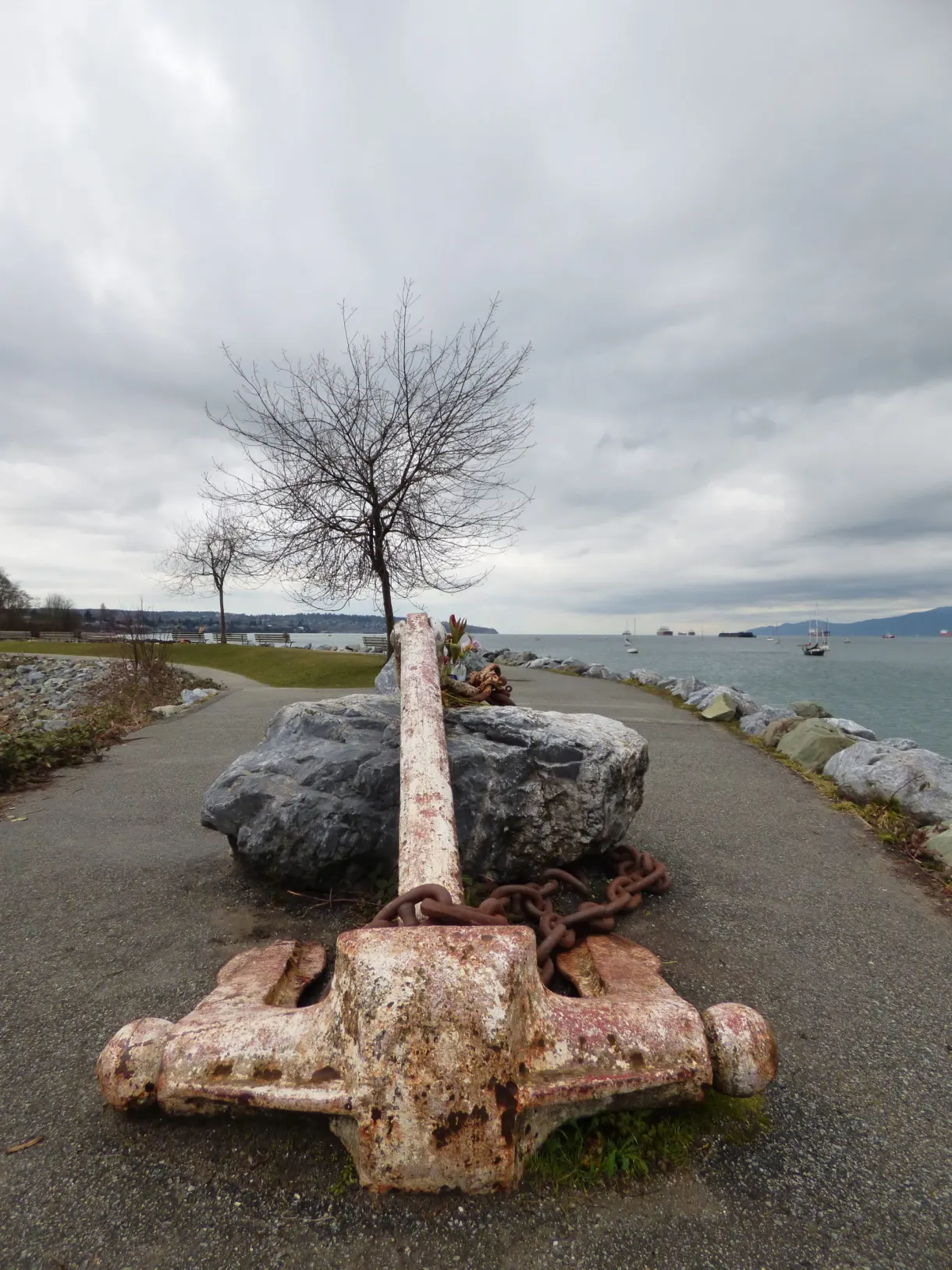 Old rusty anchor set on a rock by the path