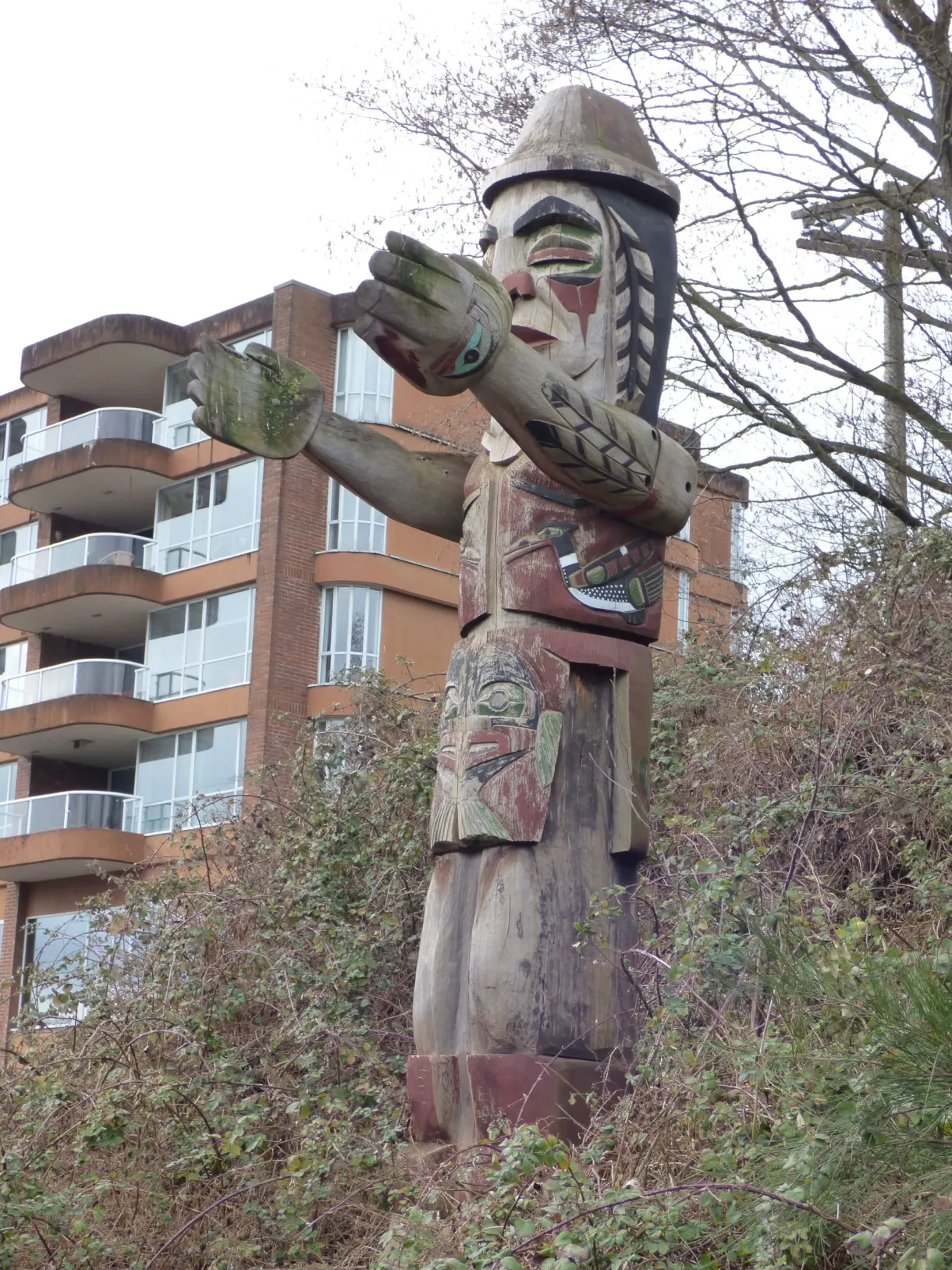 Carved totem pole standing in front of a residential building