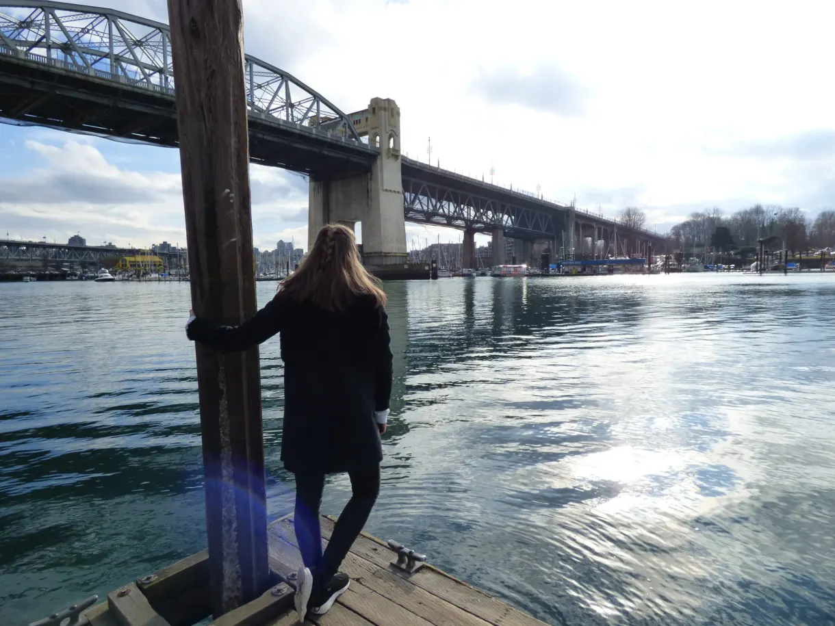 Woman leaning against a jetty pillar under the bridge